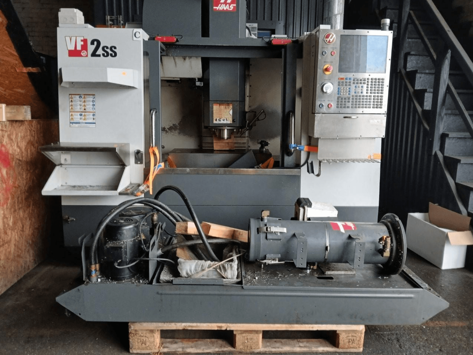 Centre d'usinage vertical HAAS VF-2SS en vue frontale, montrant le panneau de commande, la zone de la broche et les composants du moteur connectés.