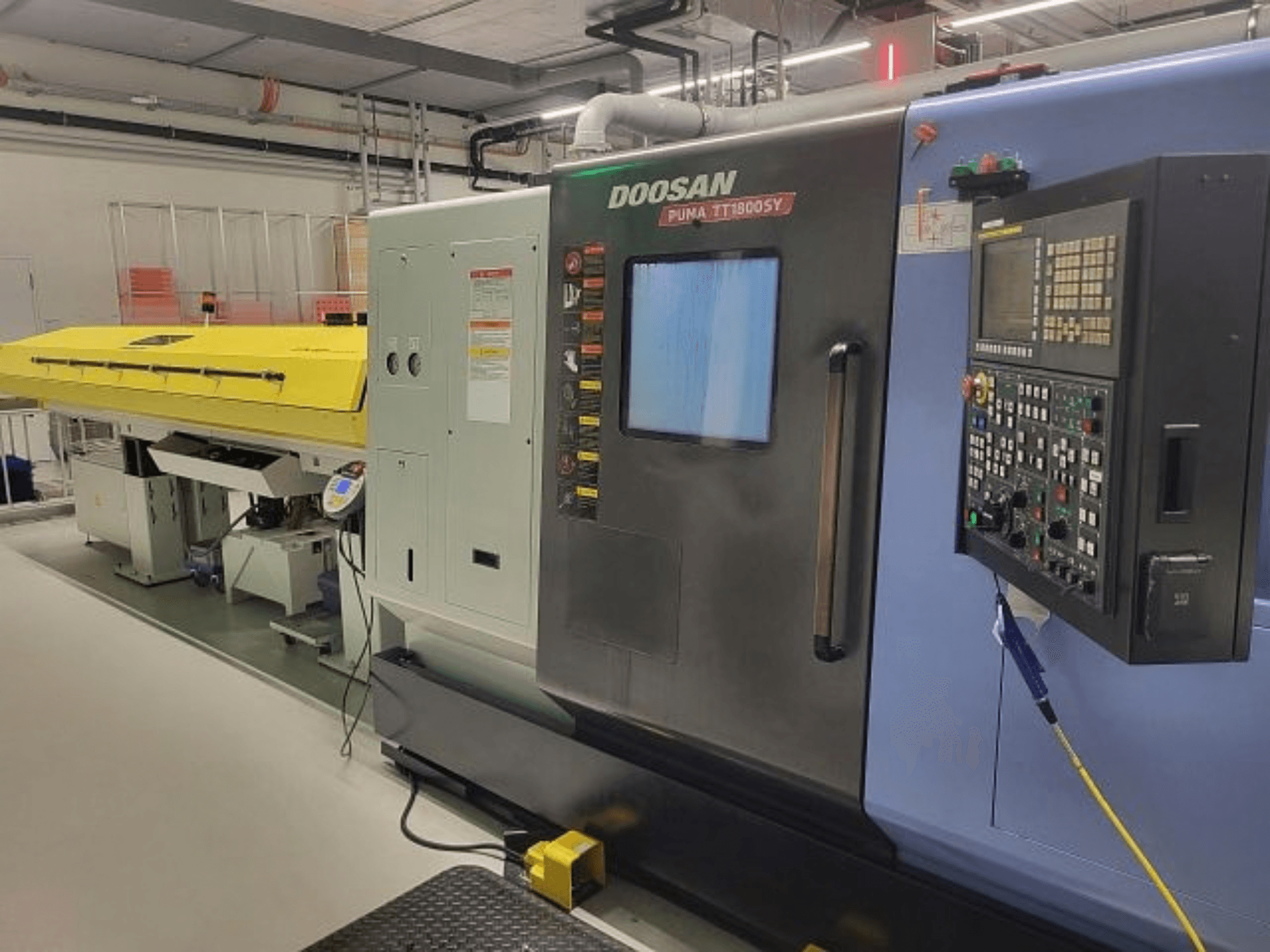 Centre de tournage-fraisage DOOSAN PUMA TT 1800 SY, vue de face avec panneau de commande et capot jaune, dans un environnement industriel.