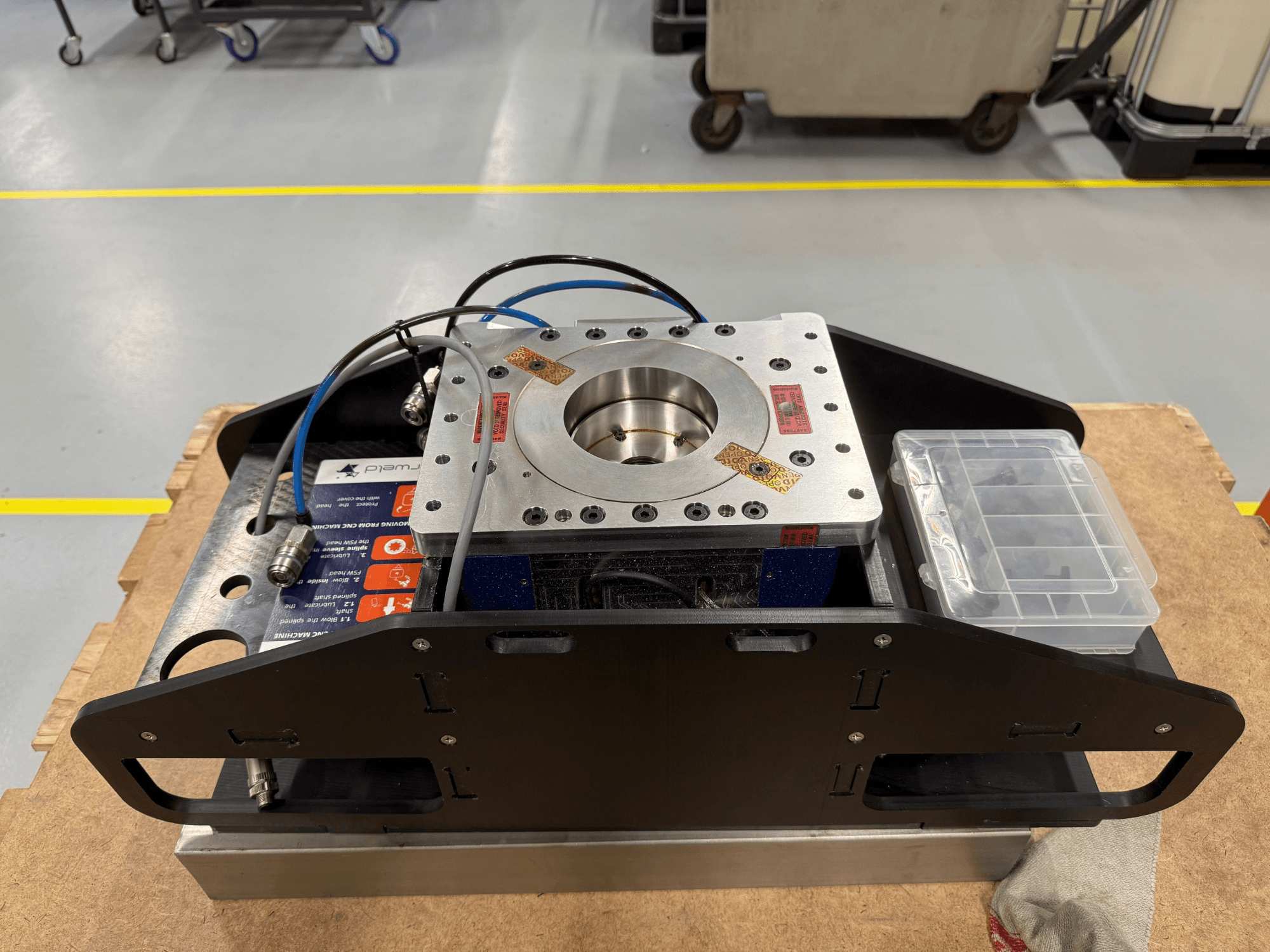 Composant en métal usiné avec câbles bleus, boîtier d'accessoires et base plate, présenté en vue de dessus, idéal pour les applications mécaniques.