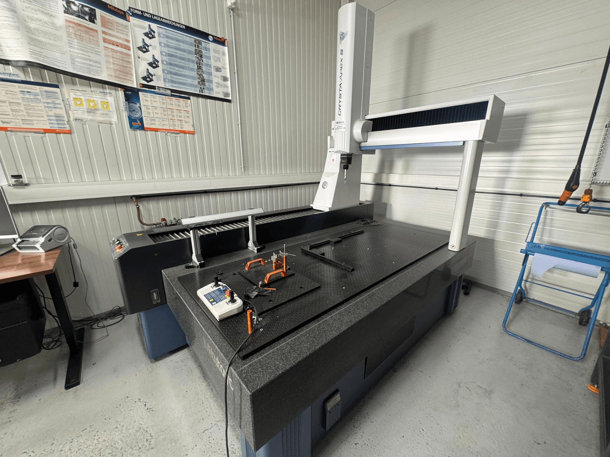 Machine à mesurer tridimensionnelle CMM de la marque Leitz, vue de face sur une surface noire texturée avec des outils de mesure.
