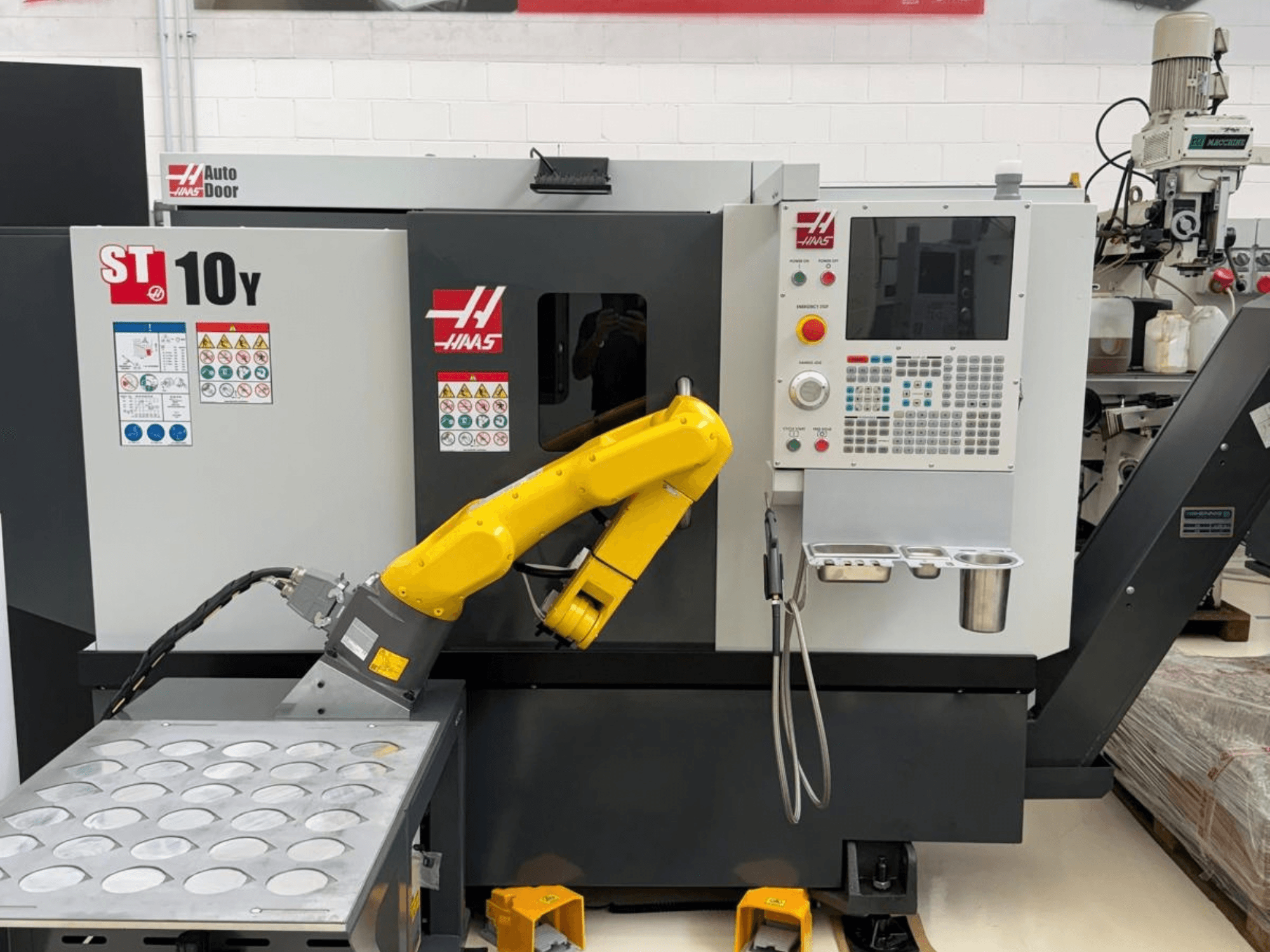 Tour horizontal Haas ST-10Y vu de face, équipé d'un bras robotisé et d'un panneau de commande avec des plateaux porte-outils.