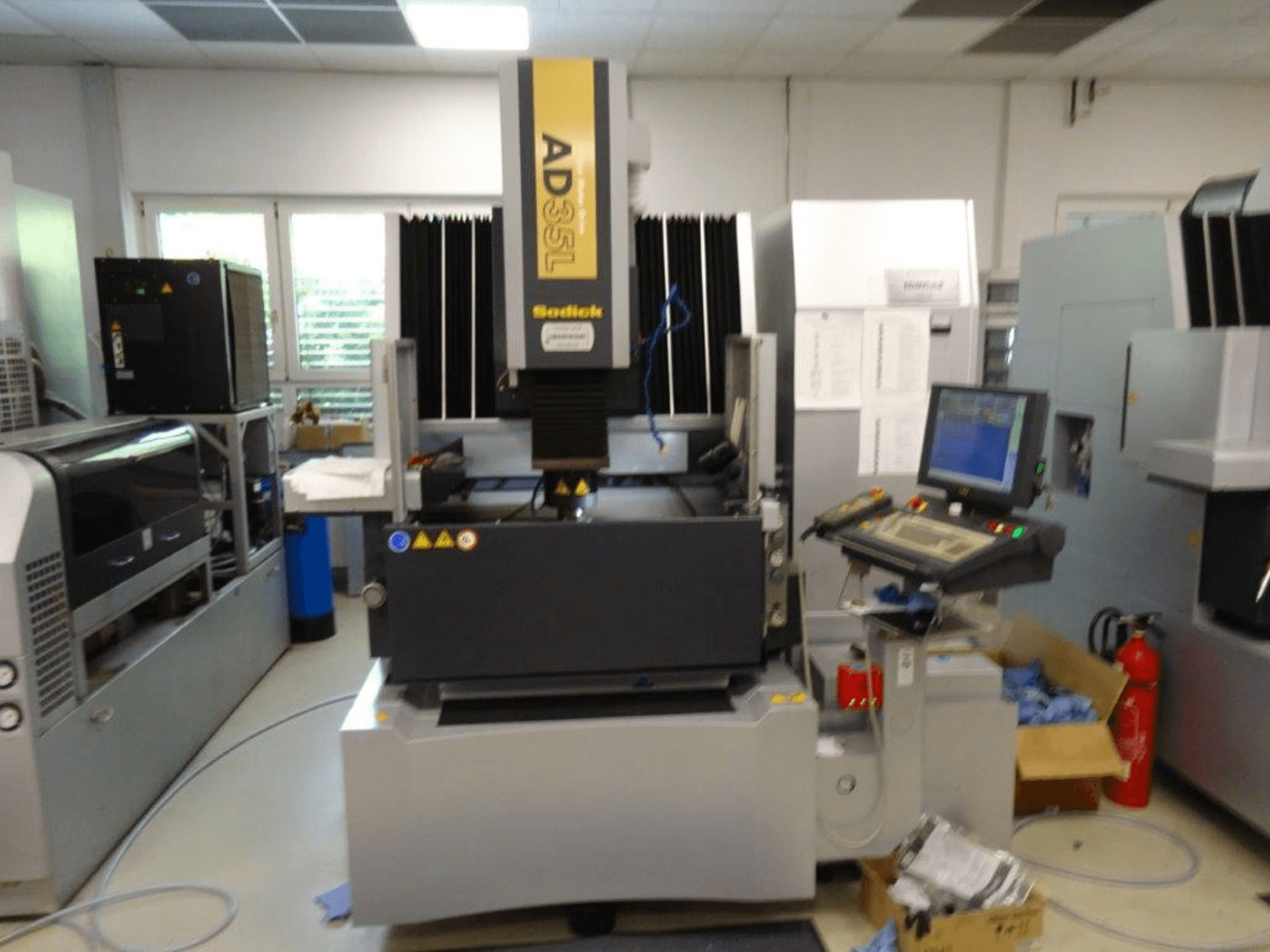 Machine CNC Sodick AD35L vue de face, avec panneau de commande, unité de refroidissement et indicateurs de sécurité.