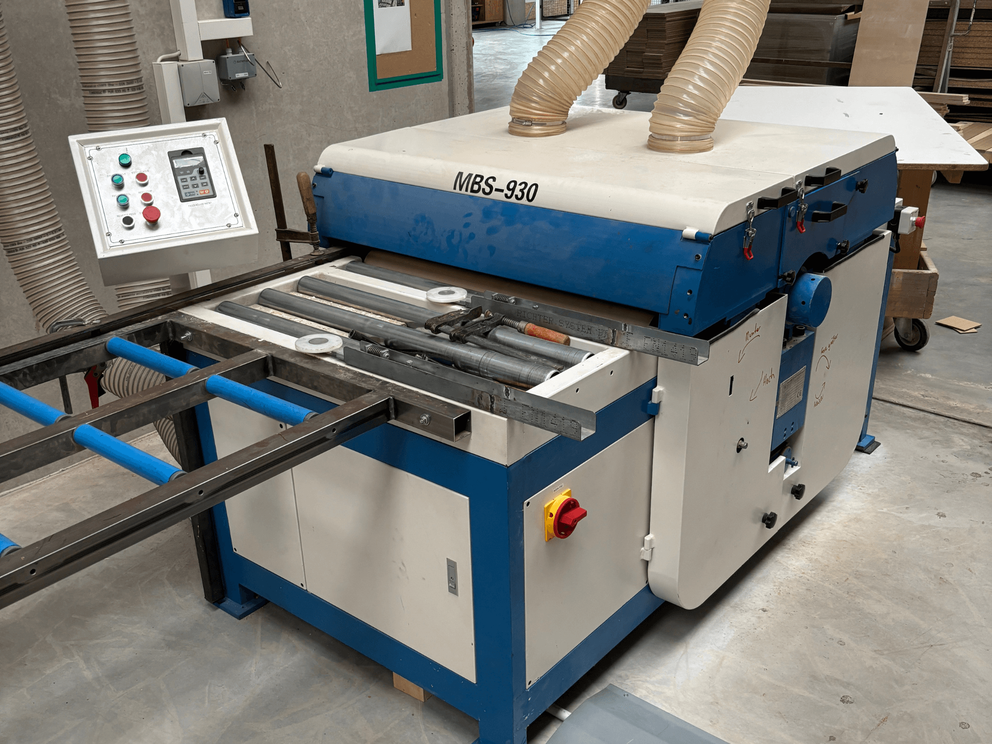 Machine à travailler le bois MBS-930 avec panneau de commande et rouleaux, vue de côté, avec tuyaux d'extraction de la poussière.