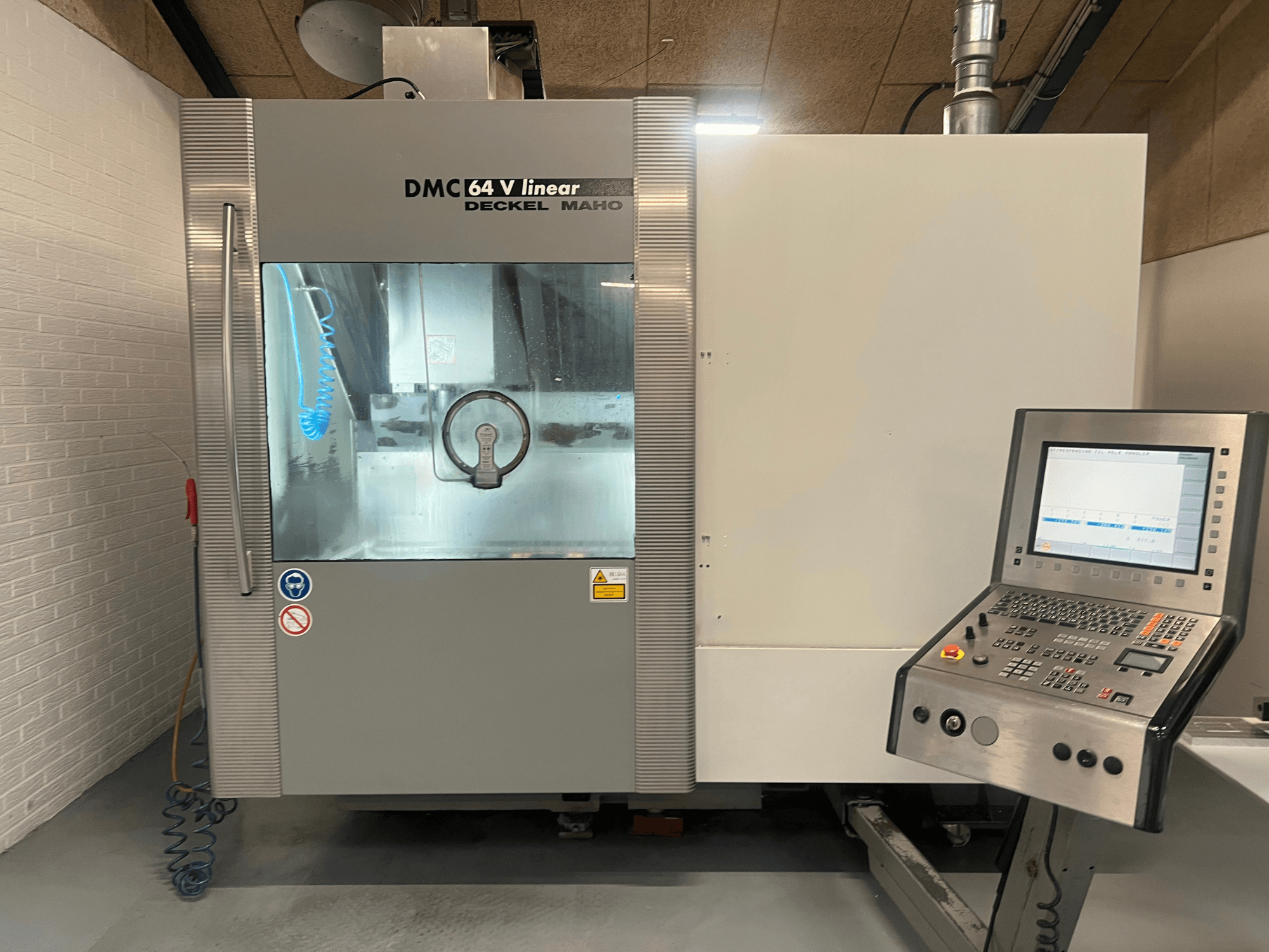DMC 64 V Linear de Deckel Maho, vue de face d'un centre d'usinage CNC avec panneau de commande et buse d'arrosage visibles.