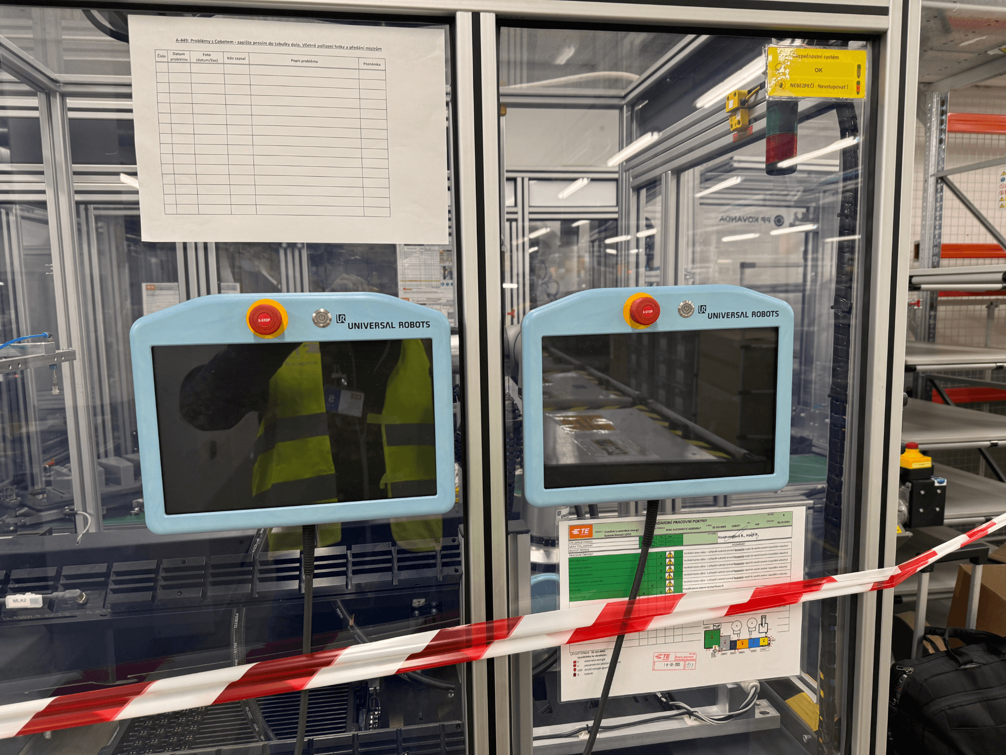 Panneau de commande pour le bras robotique UR5 e d'Universal Robots, comprenant deux moniteurs, des boutons d'arrêt d'urgence et des instructions de sécurité.