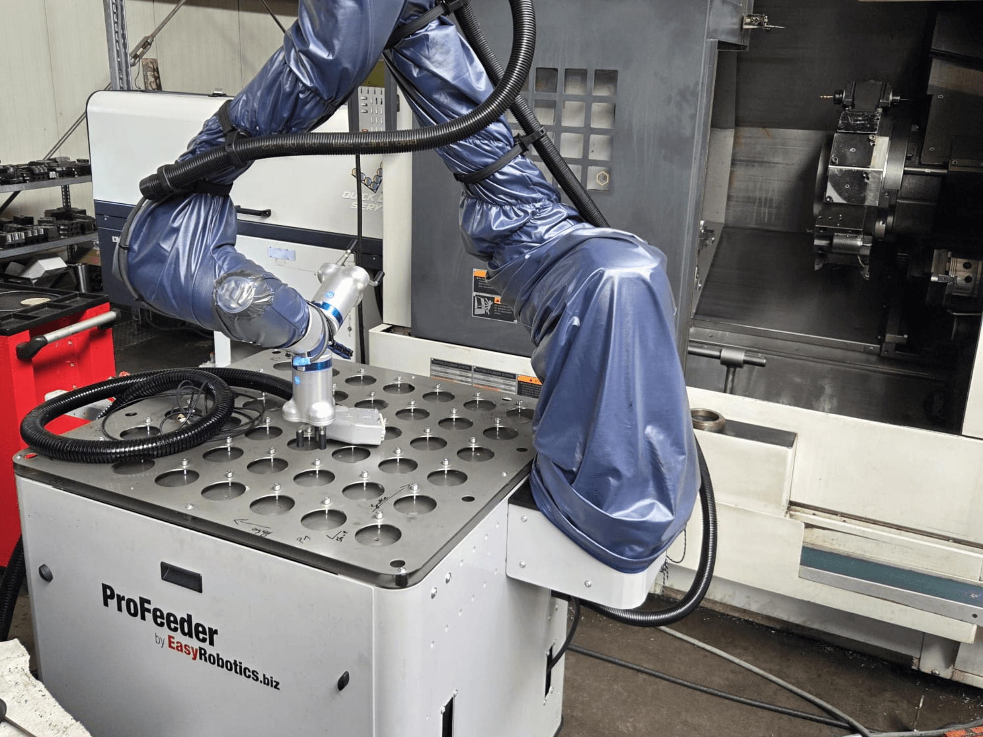 Robot collaboratif EASYROBOTICS ProFeeder vu de face, avec un bras robotique positionné au-dessus d'une table métallique perforée.