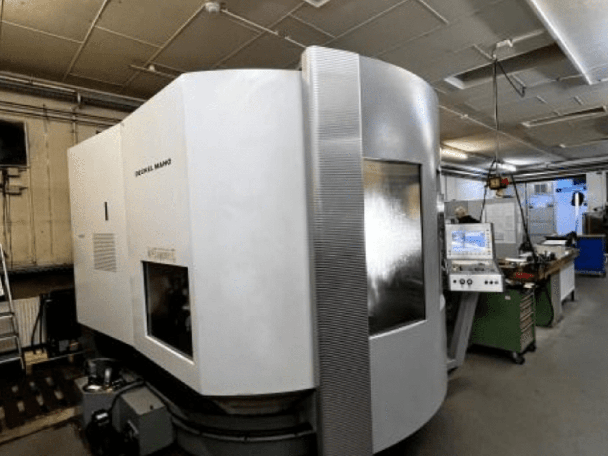 Machine CNC SODICK MAKO dans un atelier, vue latérale, avec panneau de commande et zone de travail visibles à l'arrière-plan.