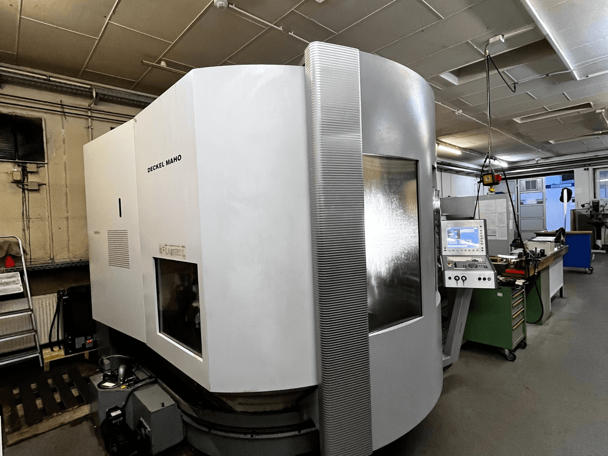 Machine CNC Deckel Maho, vue de face, extérieur blanc, panneau de commande visible, environnement d'atelier.
