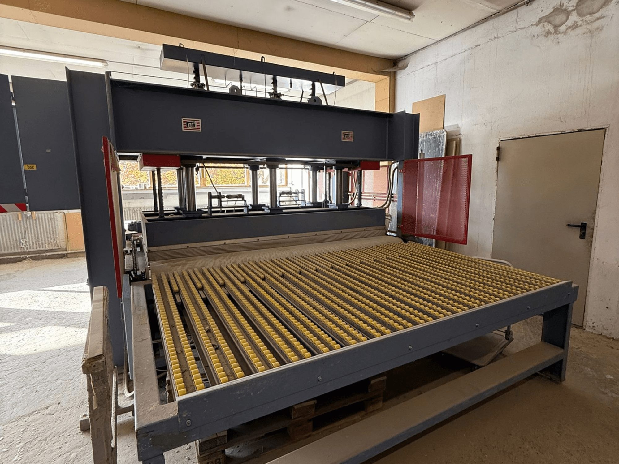 Machine industrielle à rouleaux jaunes, vue de face, logo de la marque visible, utilisée pour le traitement de matériaux dans un atelier.