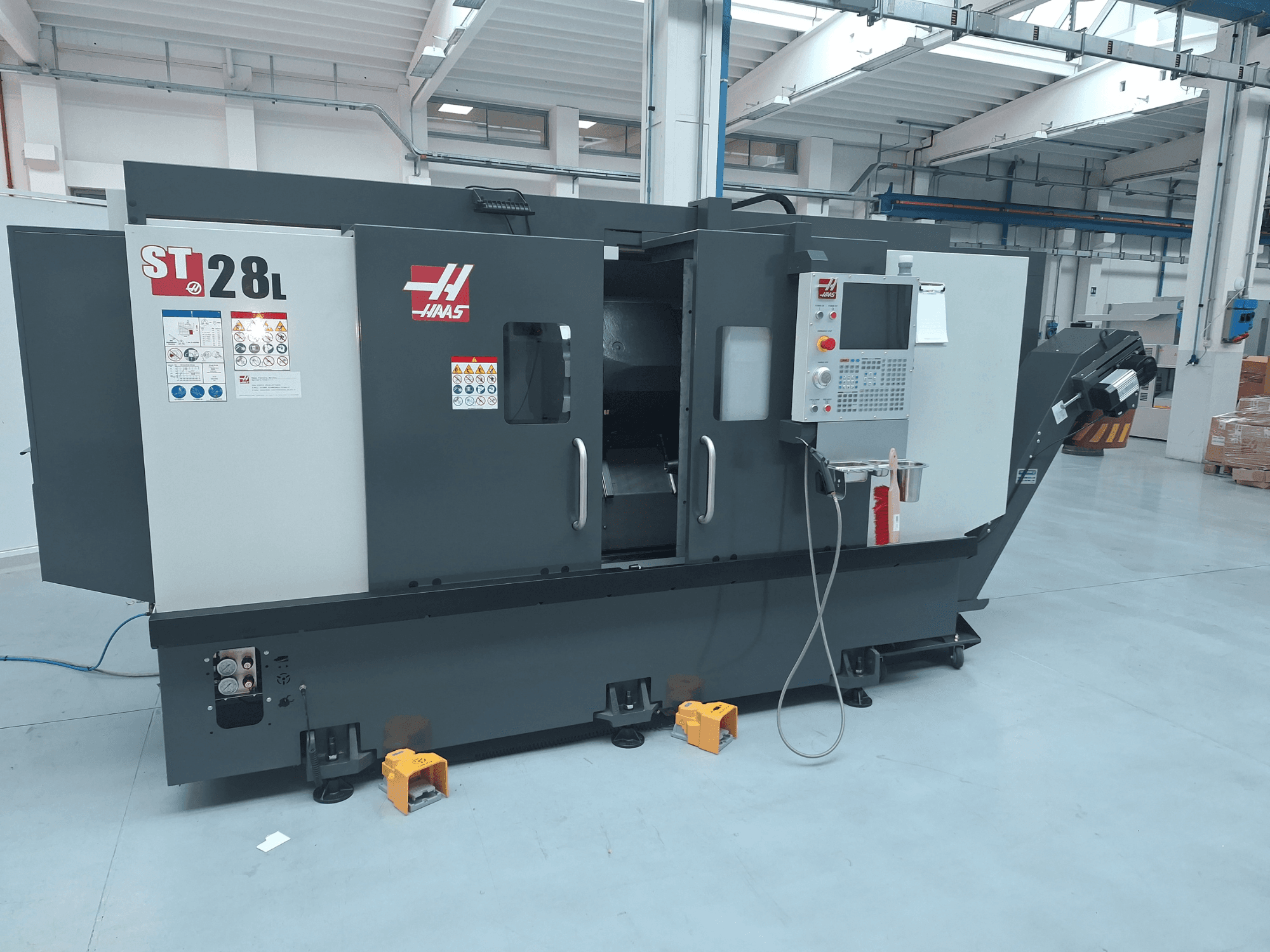 Vue latérale du tour horizontal Haas ST-28L, montrant le panneau de commande, les boutons de commande et les étiquettes de sécurité.