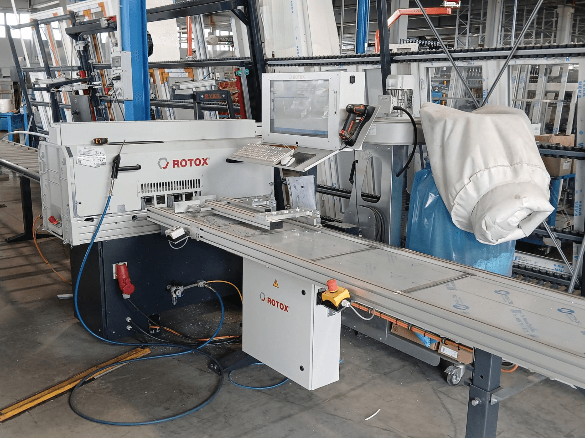 Vue de face d'une machine de transformation des matières plastiques Rotox GLA401, avec son panneau de commande, son convoyeur et ses flexibles visibles, dans un environnement industriel.