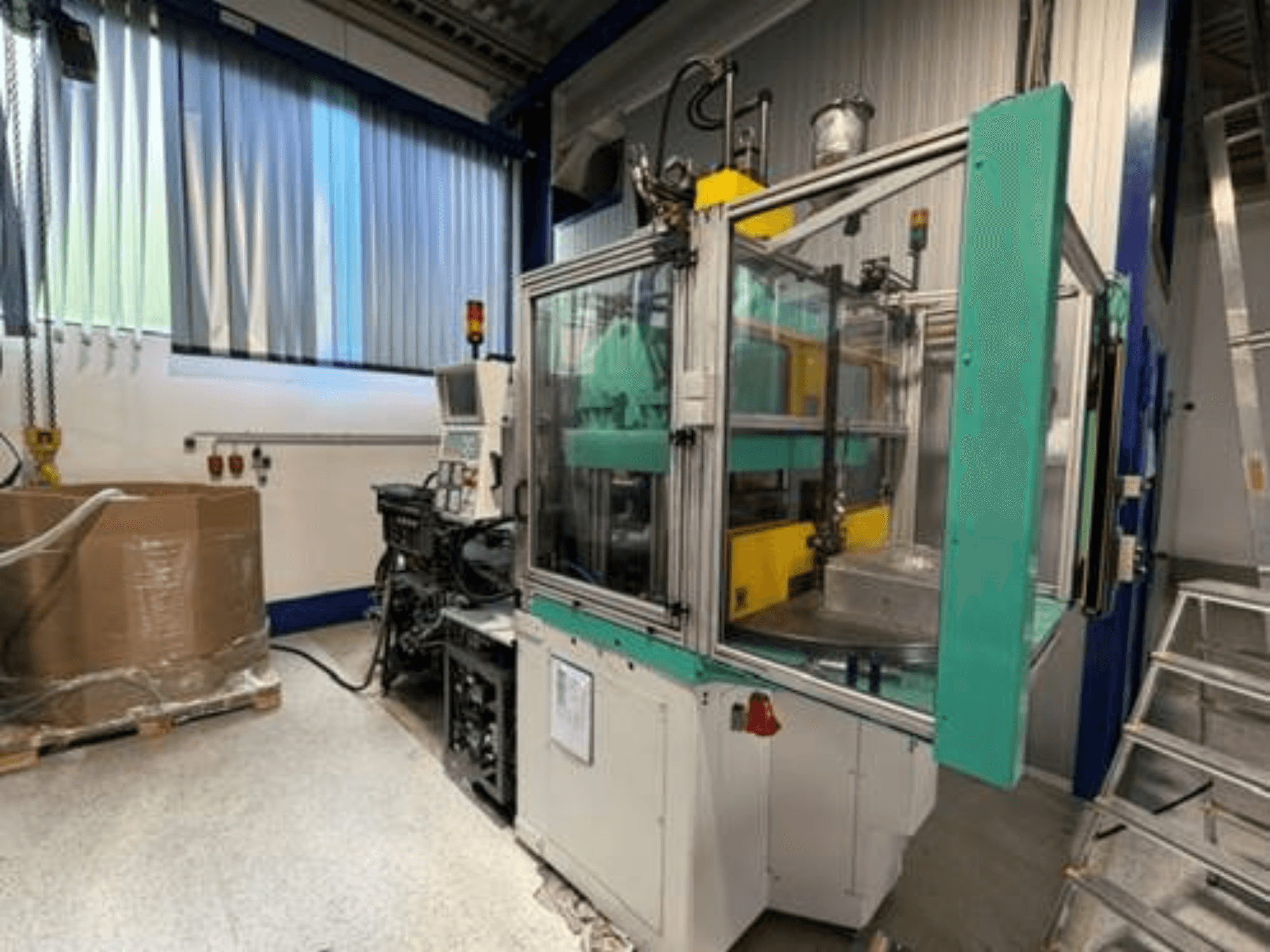 Presse à injection verticale Arburg 1200 TS 800-60-350, vue de profil, mettant en évidence le panneau de commande et l'enceinte de sécurité transparente.