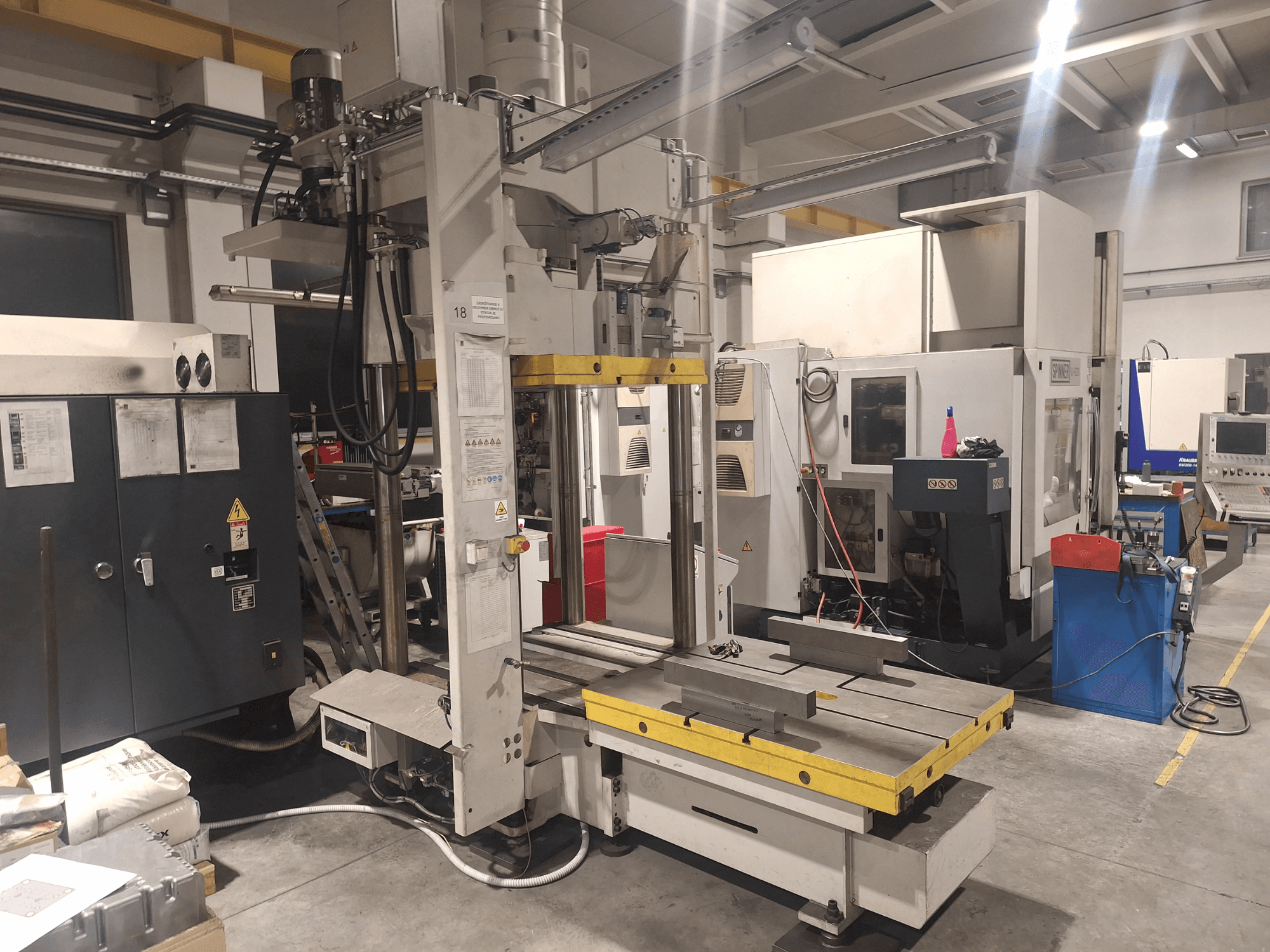 Fraiseuse horizontale de Synergic, vue de face ; elle est équipée d'une large table et de divers panneaux de commande, dans un atelier.