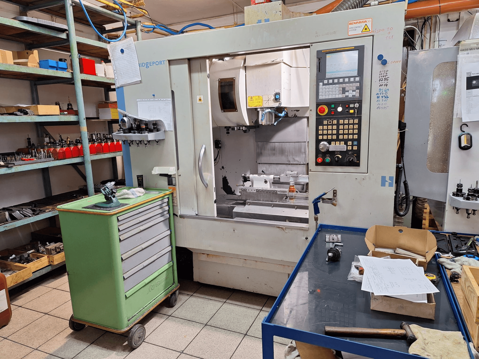 Vue de face du centre d'usinage vertical Hardinge Bridgeport GX 710, avec son panneau de commande, ses outils et ses étagères, dans un atelier.