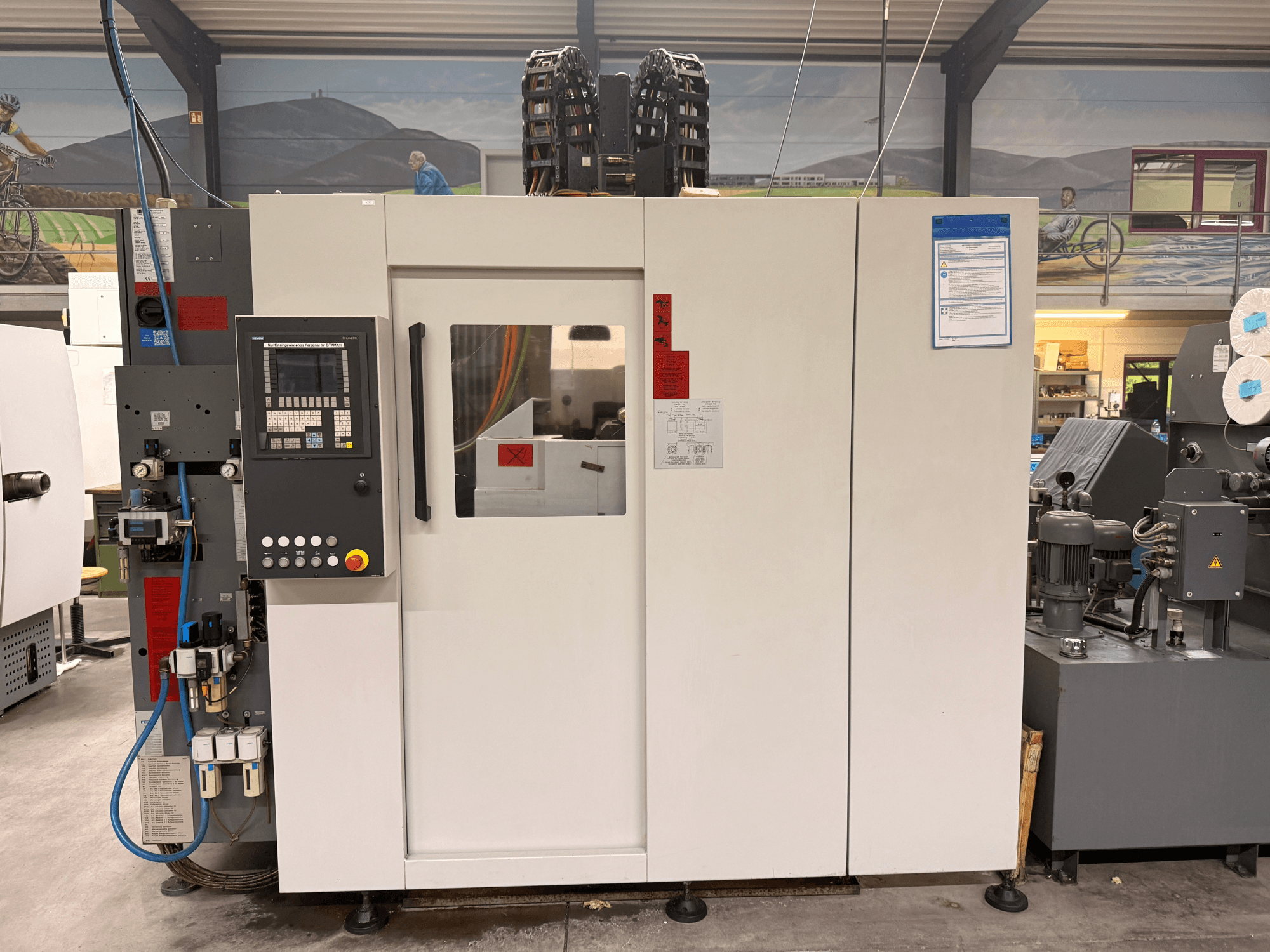 Centre d'usinage CNC blanc avec panneau de commande, vue de face, comportant des boutons et un affichage numérique, dans un atelier.