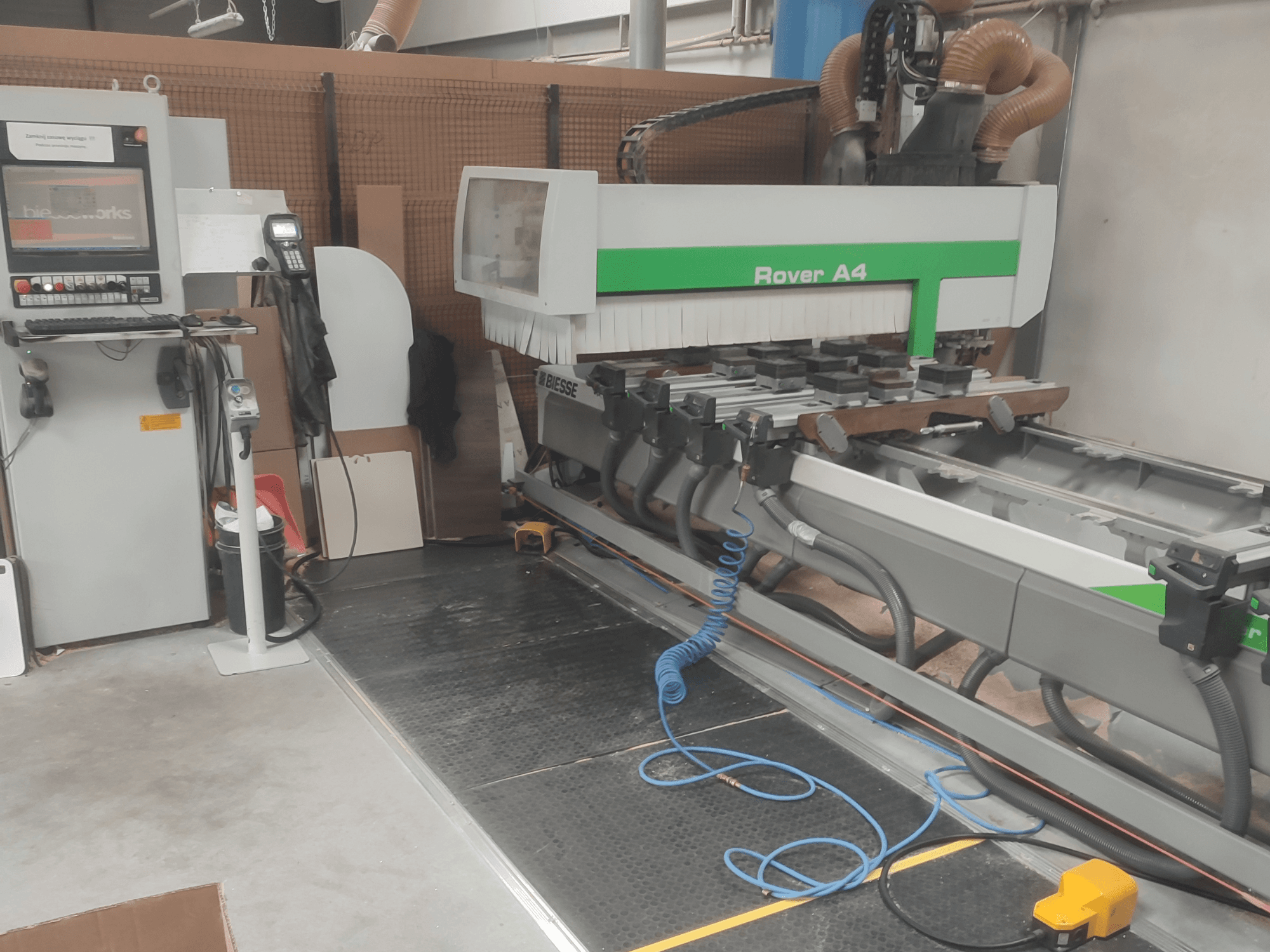 Centre d'usinage CNC BIESSE Rover A4 vu de profil, mettant en évidence le panneau de commande, les dispositifs de fixation par aspiration et le système d'aspiration des poussières.