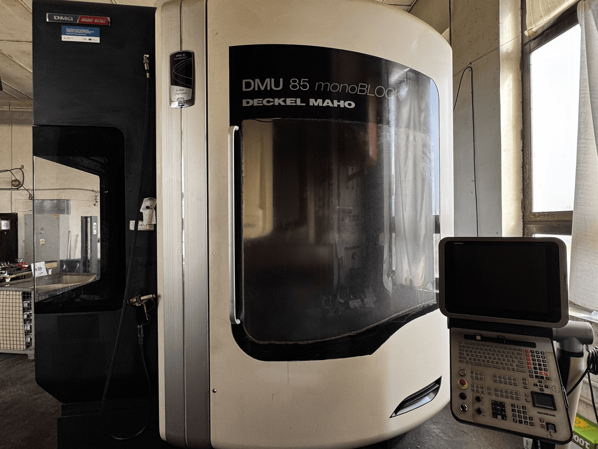Centre d'usinage vertical DMG MORI DMU 85 monoBLOCK, vue de face avec panneau de commande et grande fenêtre de visualisation.