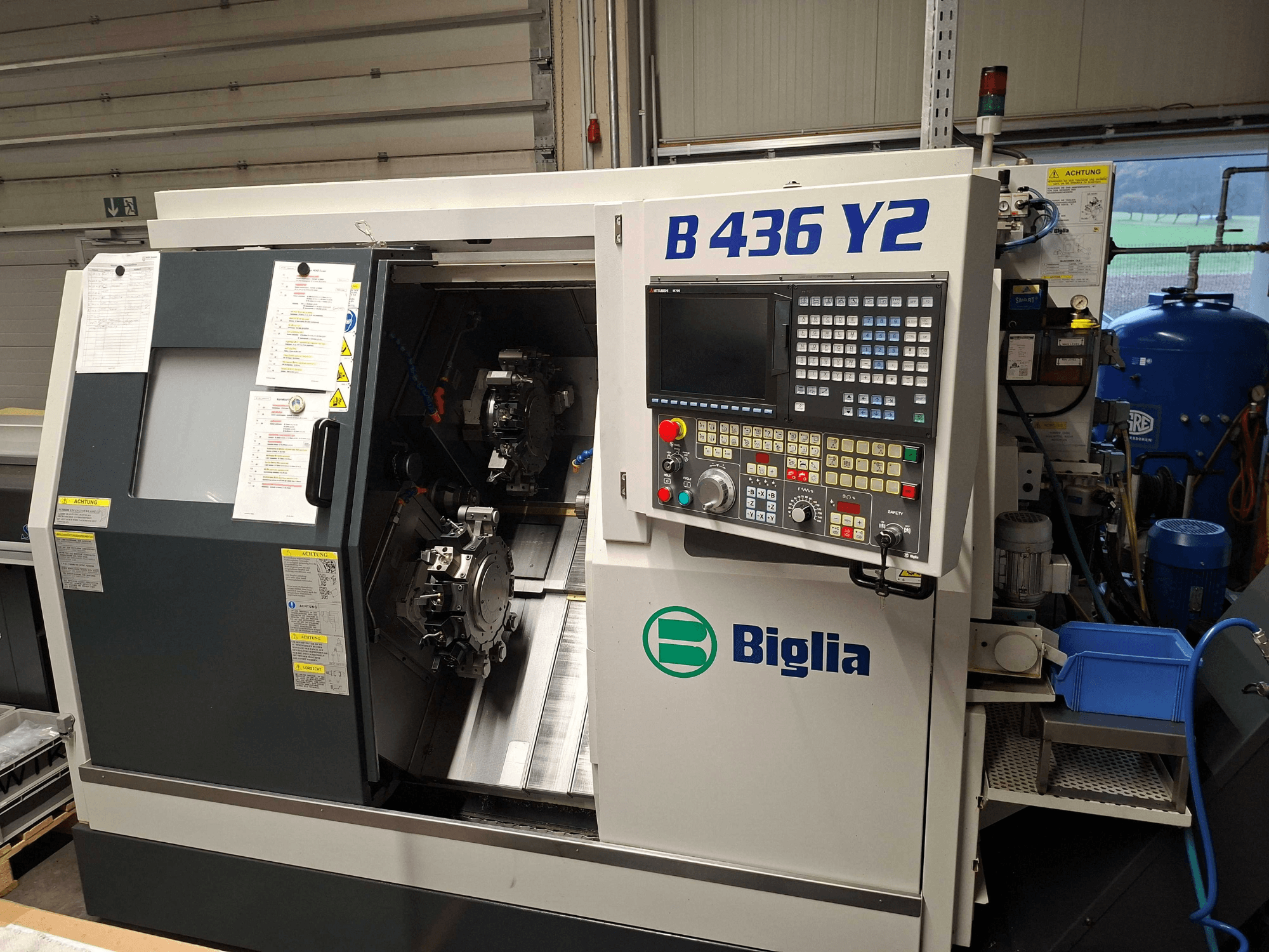 Tour CNC Biglia B 436 Y2 en vue latérale, doté de deux broches et d'un panneau de commande avec boutons et écran pour les opérations.