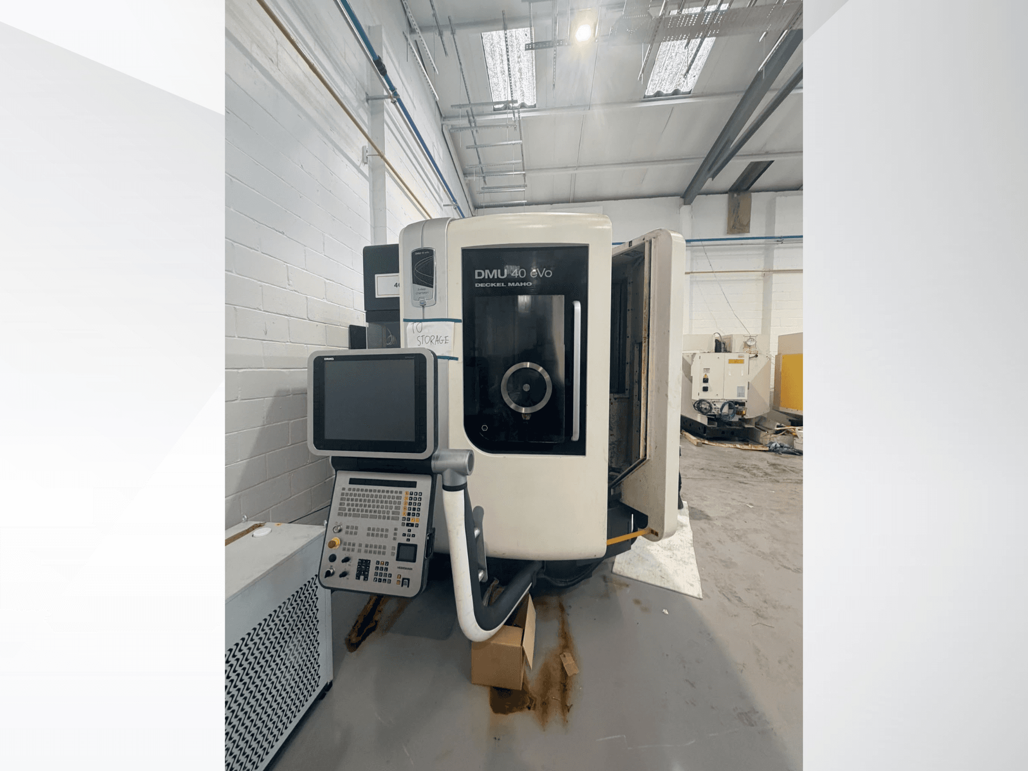 Vue de face du centre d'usinage vertical DMG DMU 40 evo, montrant le panneau de commande et la zone de la broche, avec l'espace de travail à l'arrière-plan.