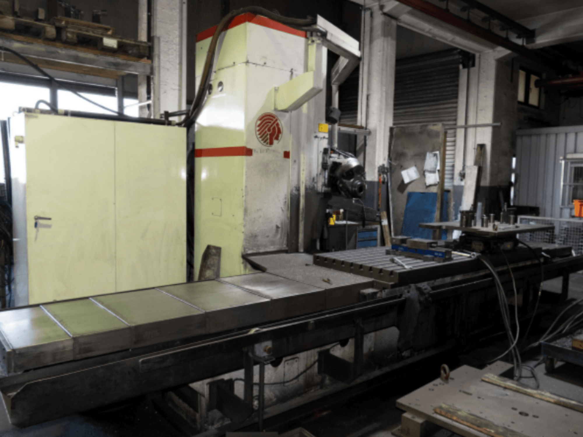 Fraiseuse industrielle avec une grande table, vue de côté, présentant les commandes et les accessoires dans un atelier.