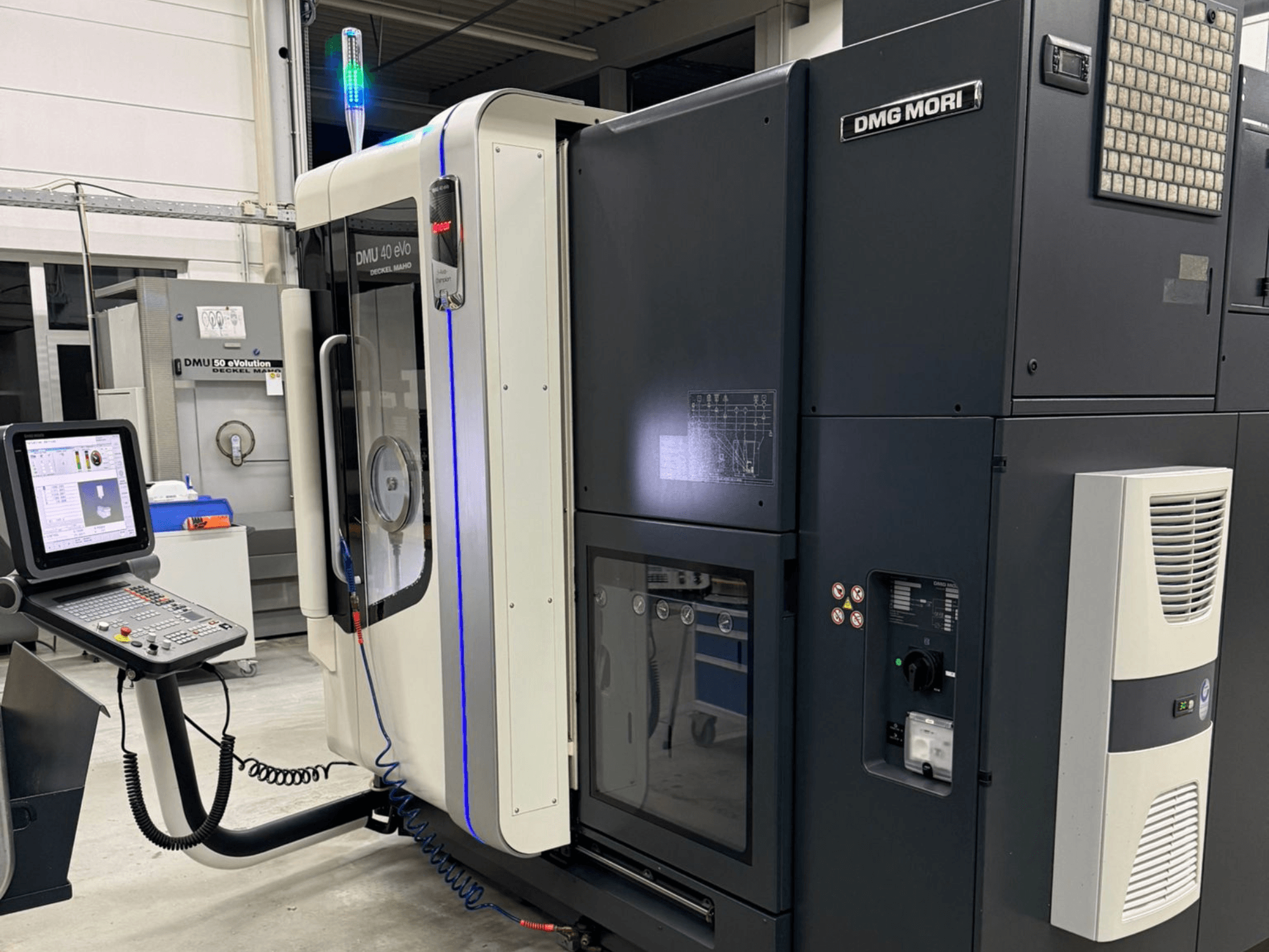 Machine DMG MORI DMU 40 eVo, vue de face montrant les commandes, les indicateurs LED et le design épuré mettant en valeur les caractéristiques industrielles.