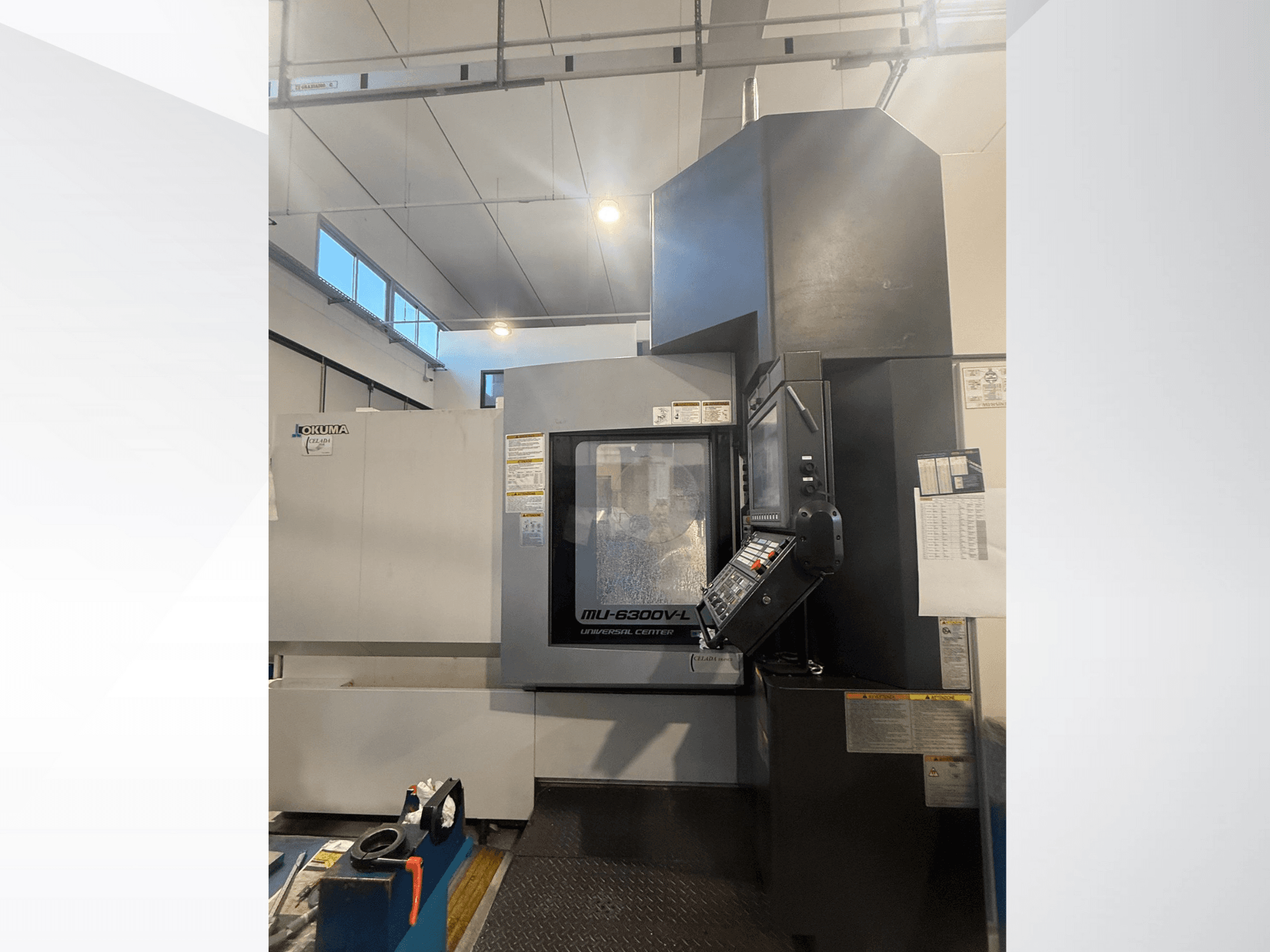 Machine CNC Okuma MU-6300V-L vue de l'avant, présentant le panneau de commande et les étiquettes de sécurité.