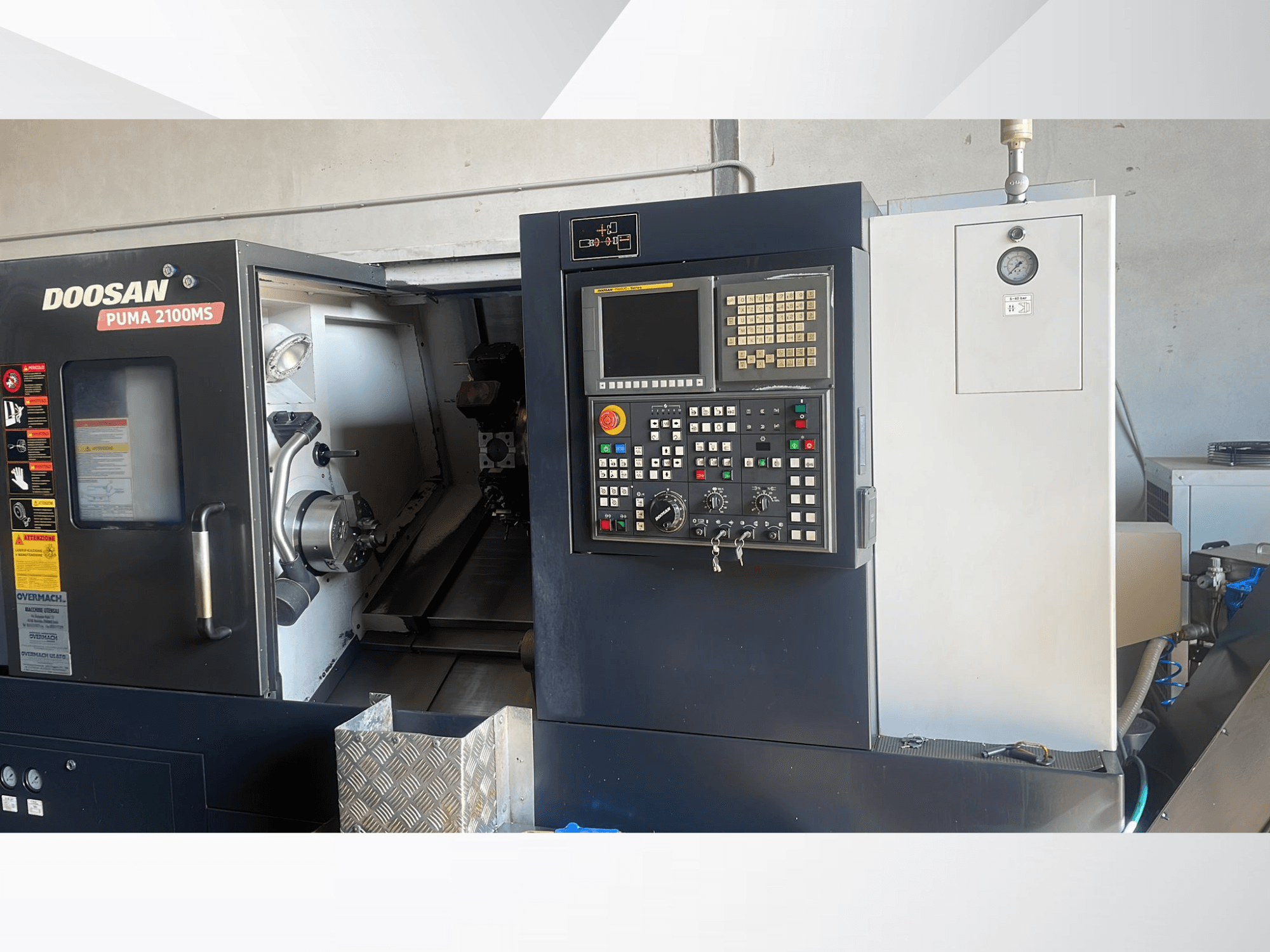 Vue de face du tour horizontal DOOSAN PUMA 2100MS, montrant le panneau de commande, la broche et les outils de coupe à l'intérieur de la chambre.