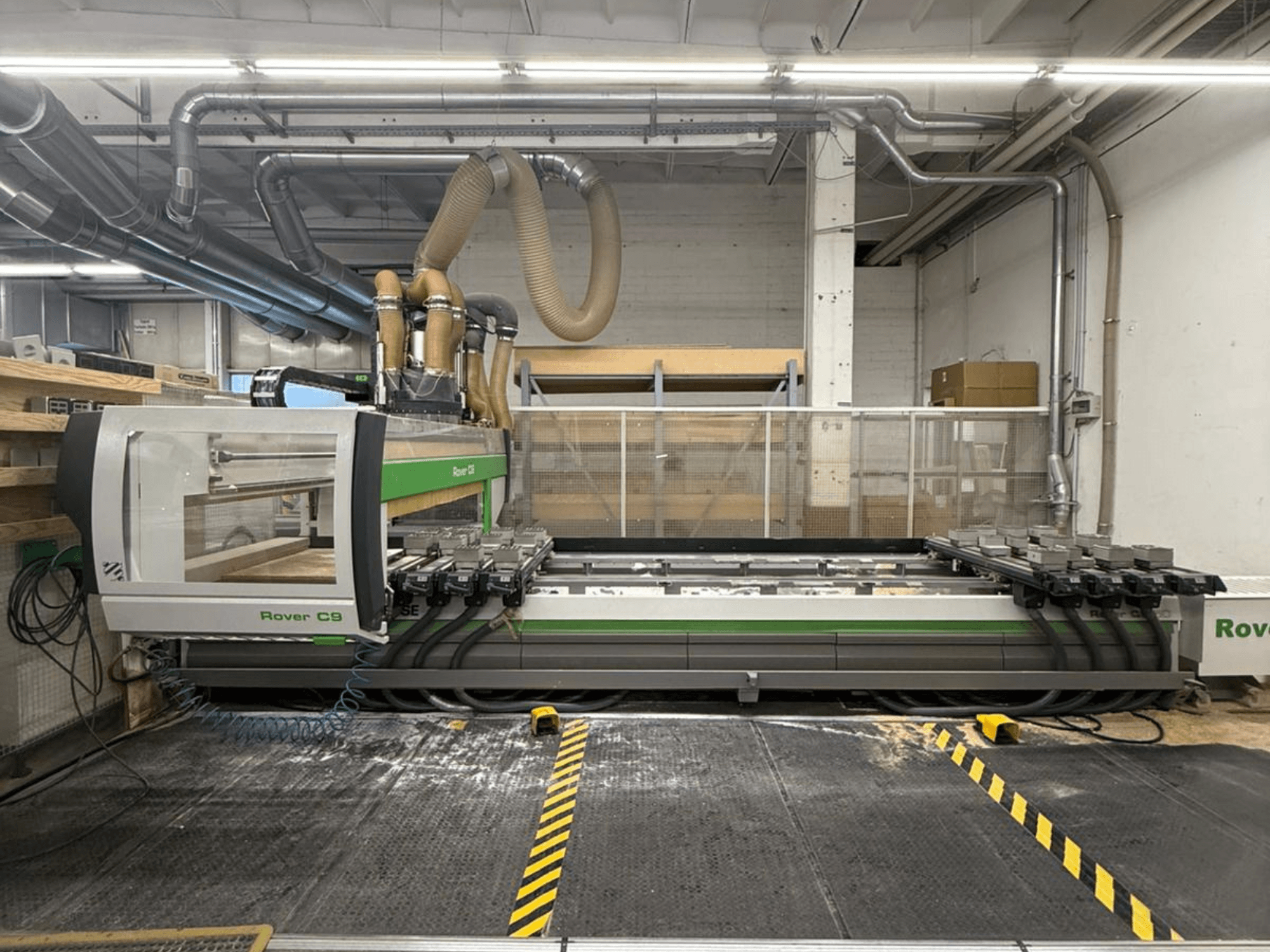Machine CNC Rover C9 dans un atelier, vue de face, avec plusieurs têtes de coupe et un système d'extraction des poussières visible.