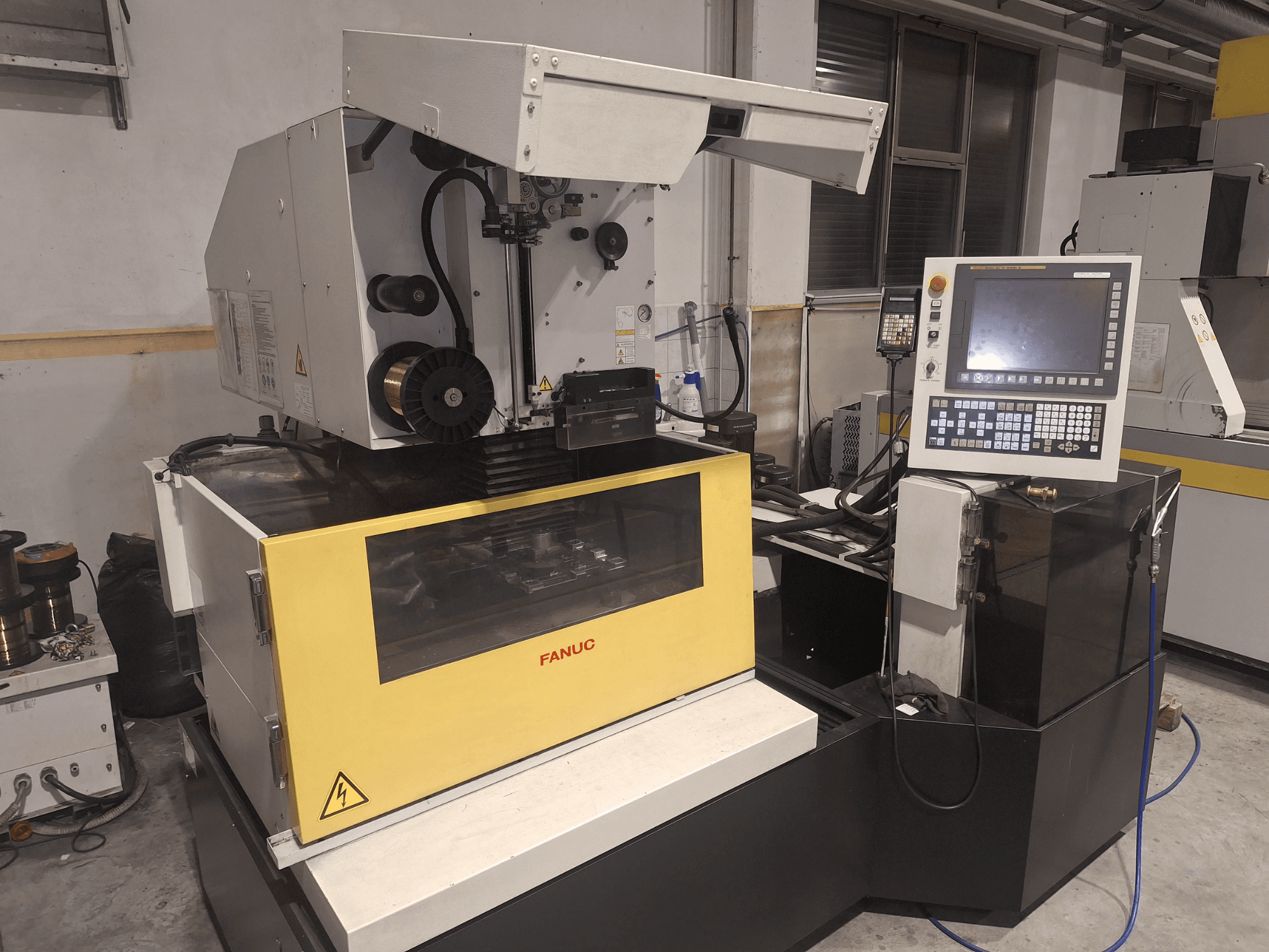 Machine CNC FANUC vue de face avec le couvercle ouvert, révélant la zone de travail et le panneau de commande à droite.