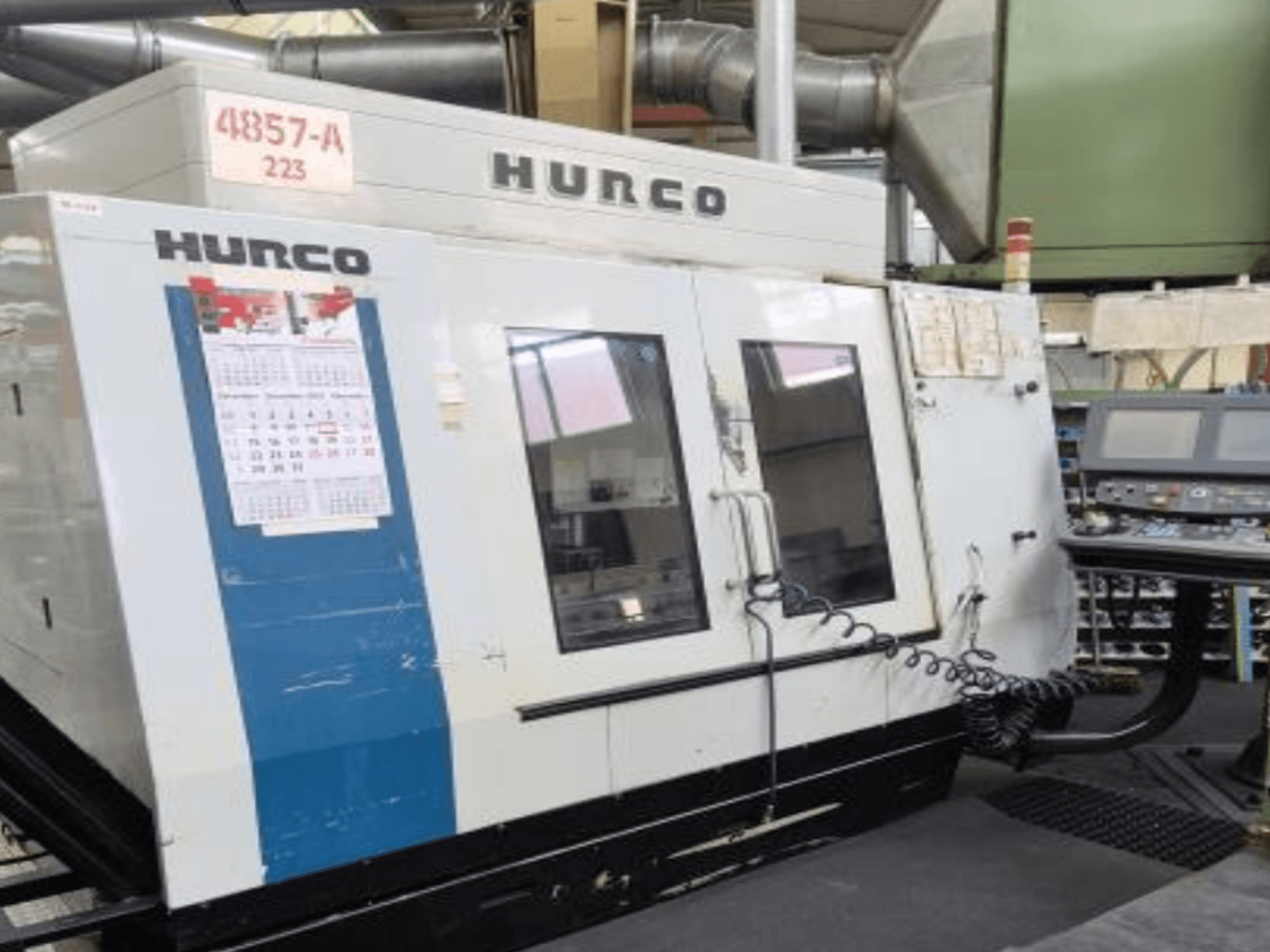 Centre d'usinage vertical Hurco VMX 42 en vue de face, avec panneau de commande, calendrier et détails extérieurs en métal.