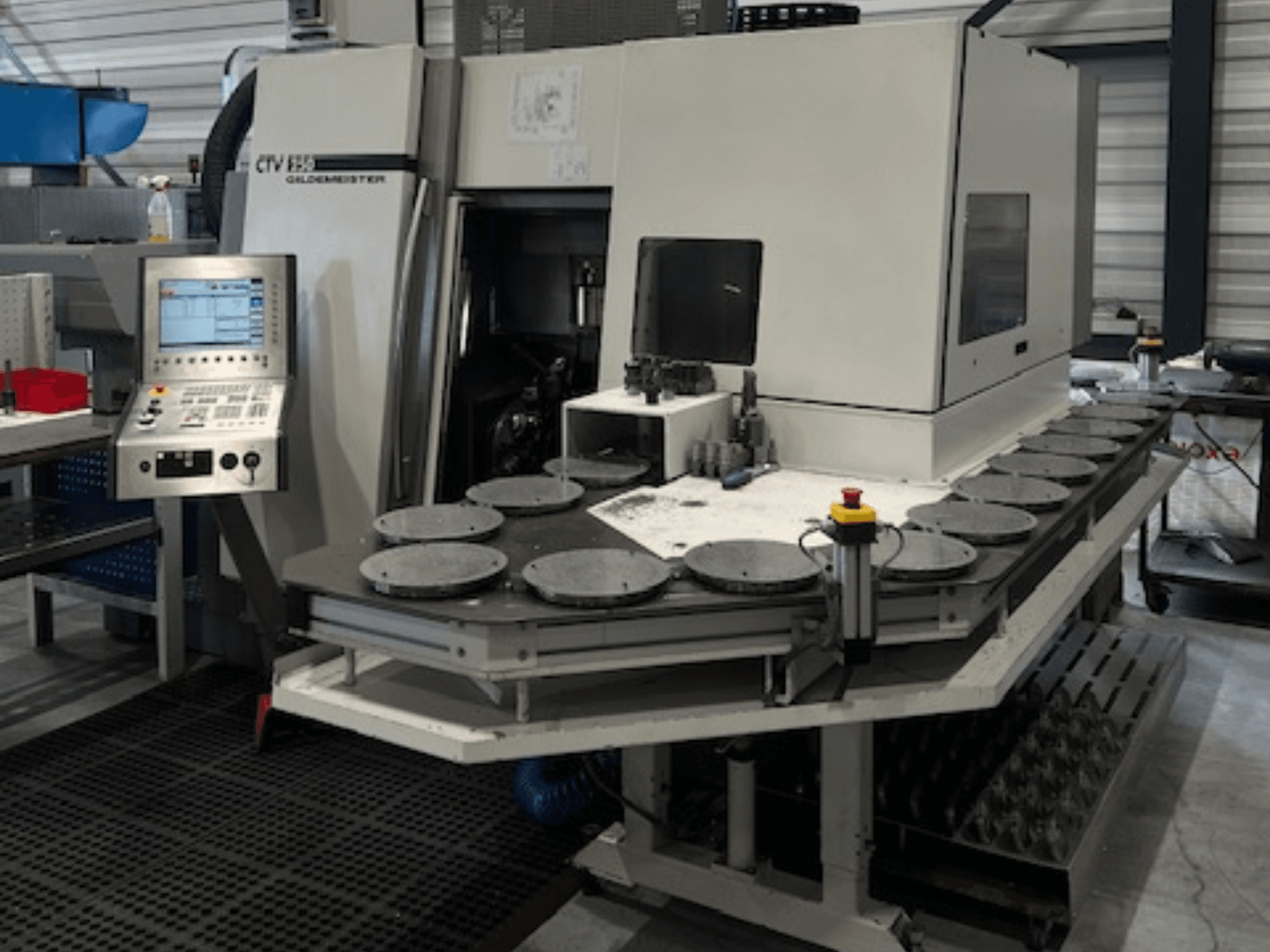 Alt text : CTV E33 Unité d'usinage Goldmeister dans un atelier, vue de face, avec panneau de commande et plusieurs plates-formes de travail circulaires.