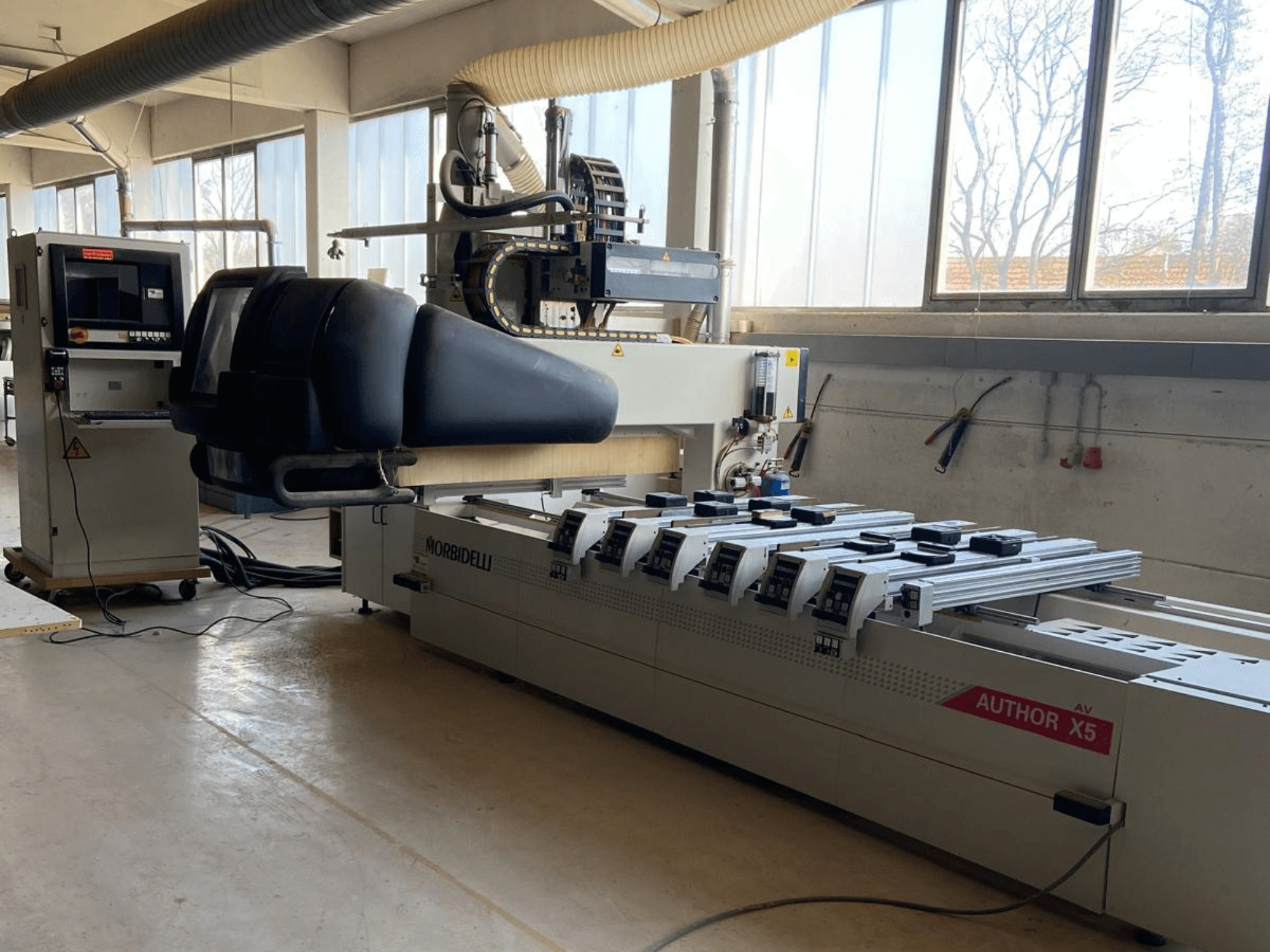 Centre d'usinage du bois CNC MORBIDELLI Author X5 dans un atelier, montrant le panneau de commande et la zone d'usinage d'une vue latérale.