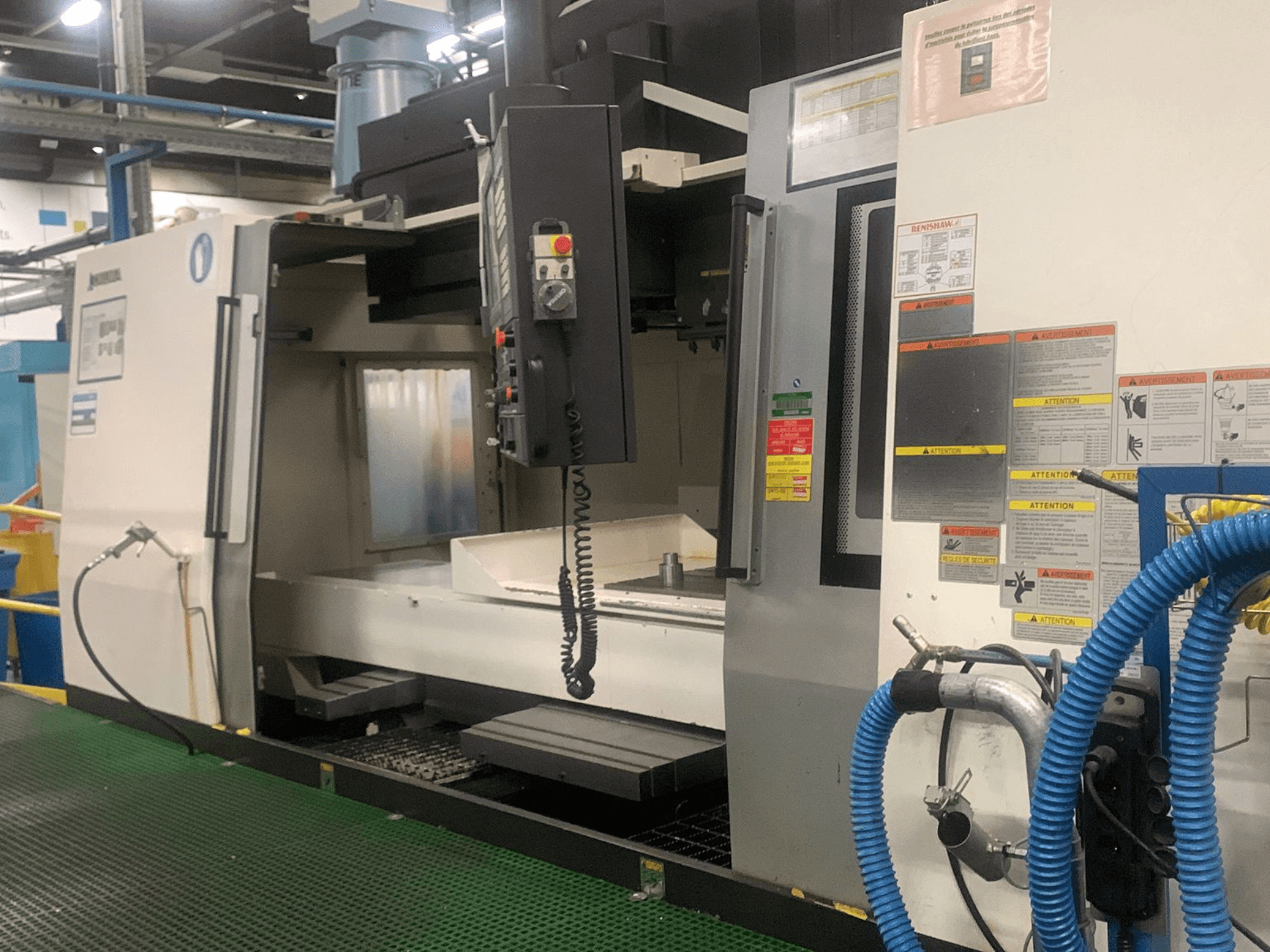 Centre d'usinage vertical Okuma Millac 852 VII, vue de face, montrant le panneau de commande, la zone de la broche et les étiquettes de sécurité.