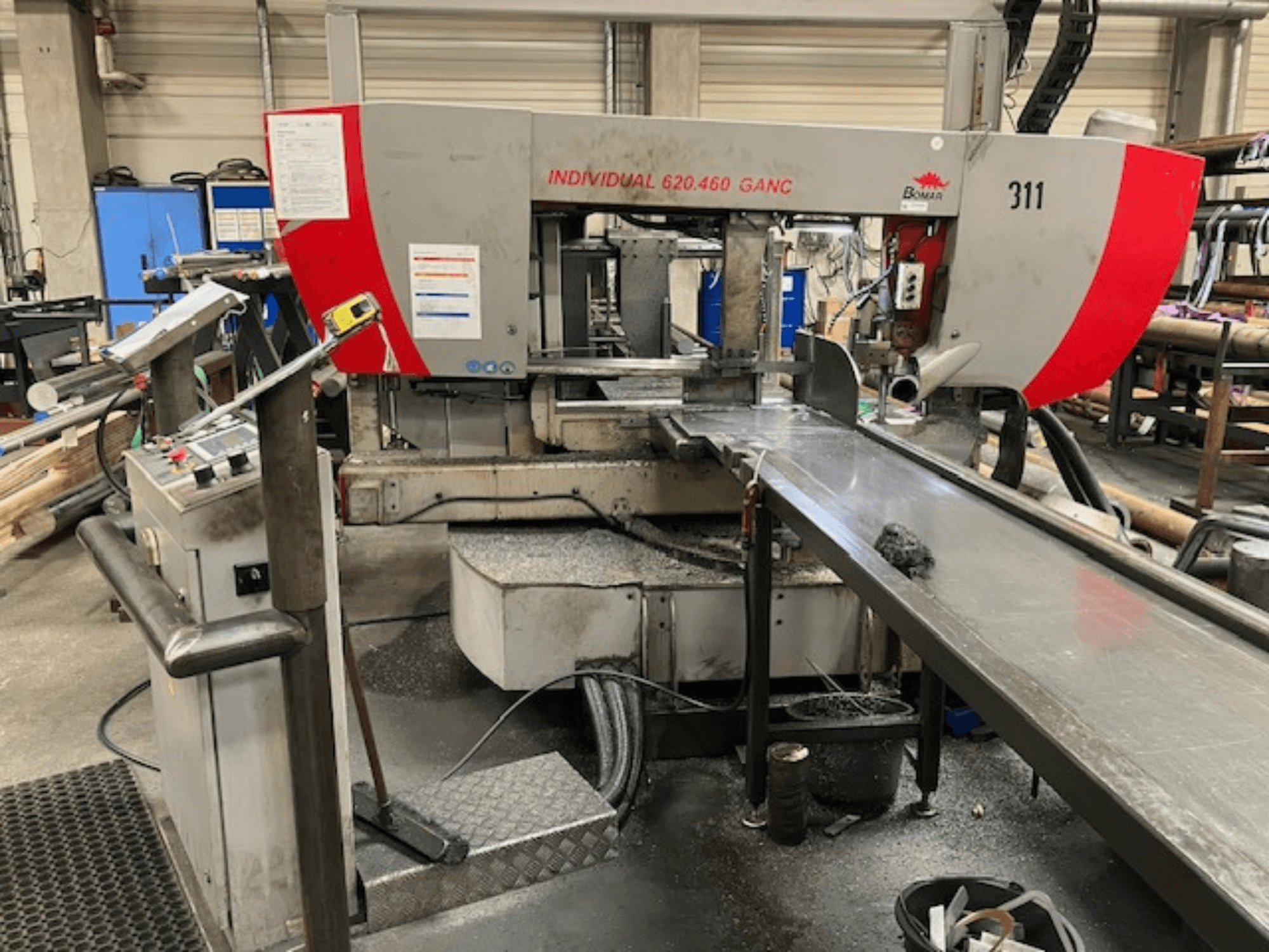 Scie à ruban BOMAR INDIVIDUAL 620-460 GANC, vue de face, montrant les commandes, la zone de coupe et l'arrière-plan d'un atelier industriel.