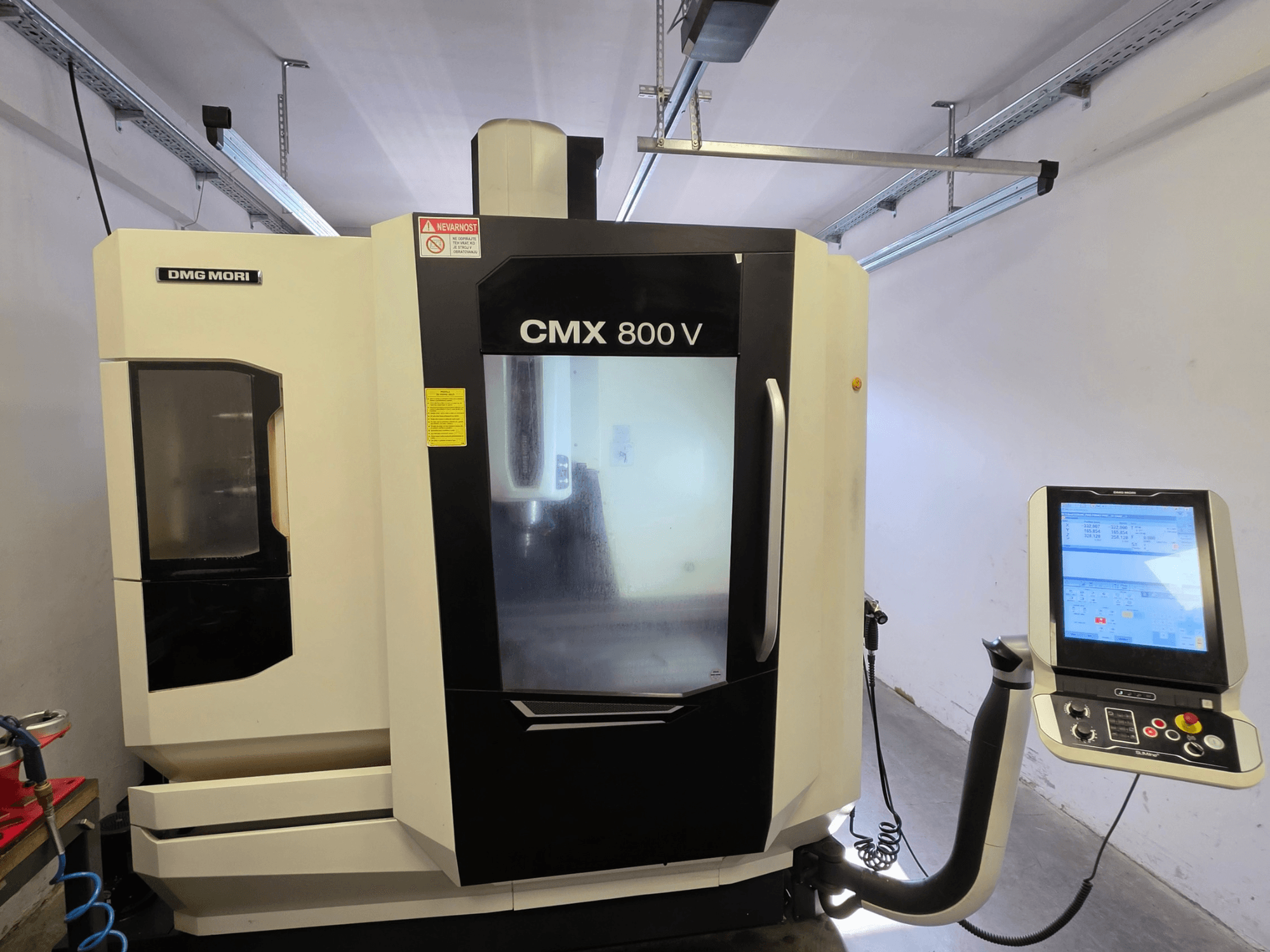 Centre d'usinage vertical DMG MORI CMX 800V, vue de face, équipé d'un panneau de commande à écran tactile et d'une signalétique de sécurité claire.