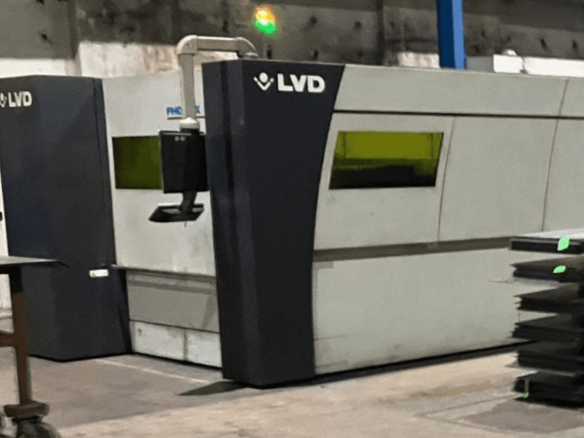 Machine de découpe laser industrielle LVD dans une usine, vue de face montrant son design épuré et ses voyants lumineux verts de fonctionnement.