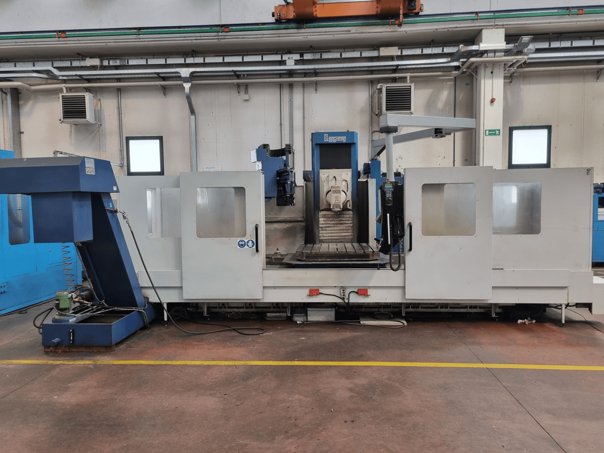 Fraiseuse CNC de "Brembana", vue latérale montrant le panneau de commande et la zone opérationnelle avec une table de travail à l'intérieur.