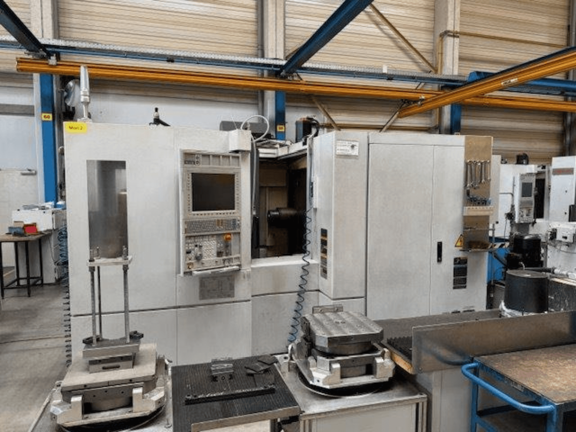 MORI SEIKI NH4000 DCG vue de face d'un centre d'usinage horizontal avec panneau de commande et pièces à usiner sur la table.