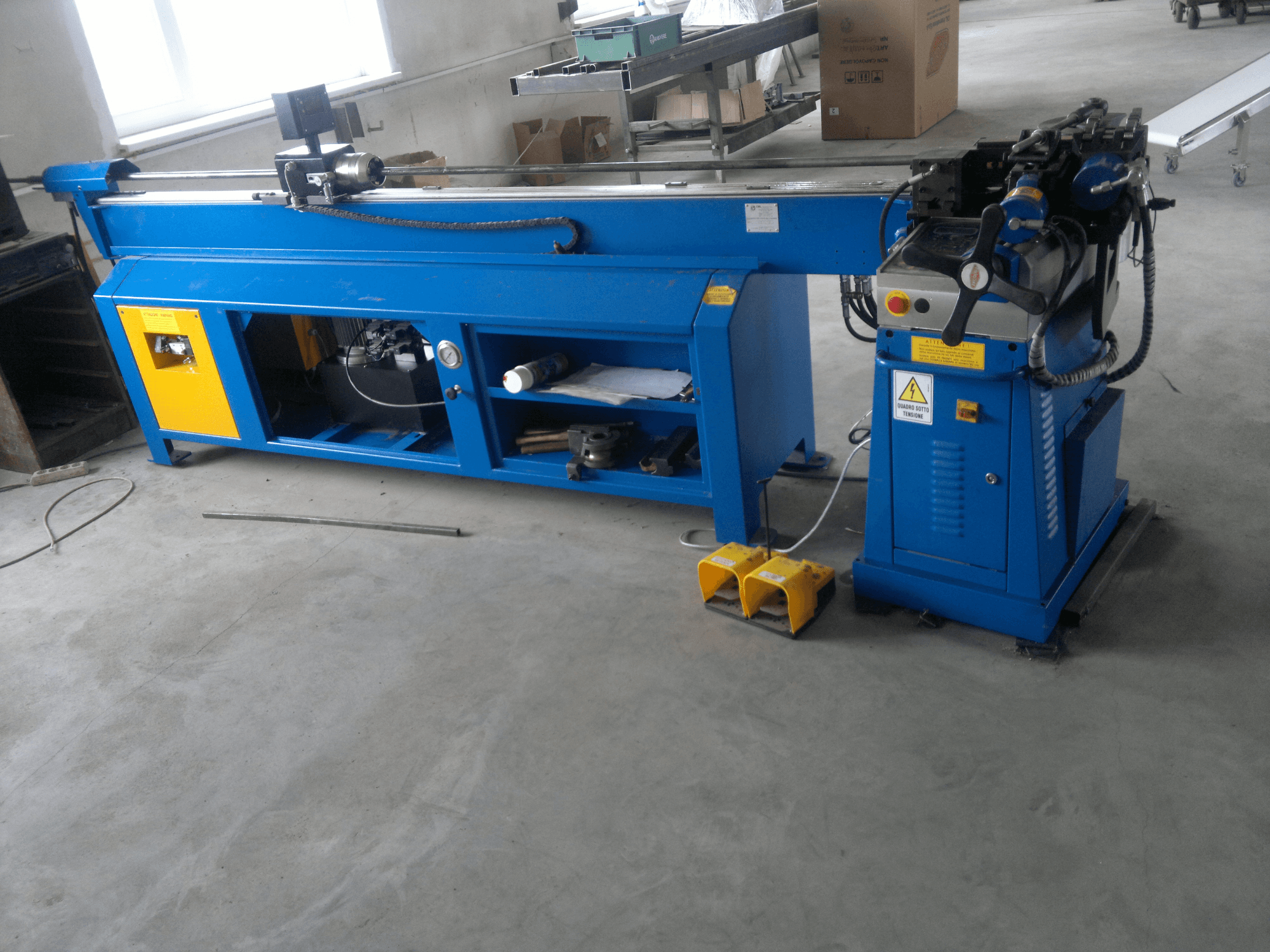 Machine à travailler le bois bleue avec des accents jaunes, vue de côté ; comprend un panneau de commande, des pédales et un ensemble de lames rotatives.