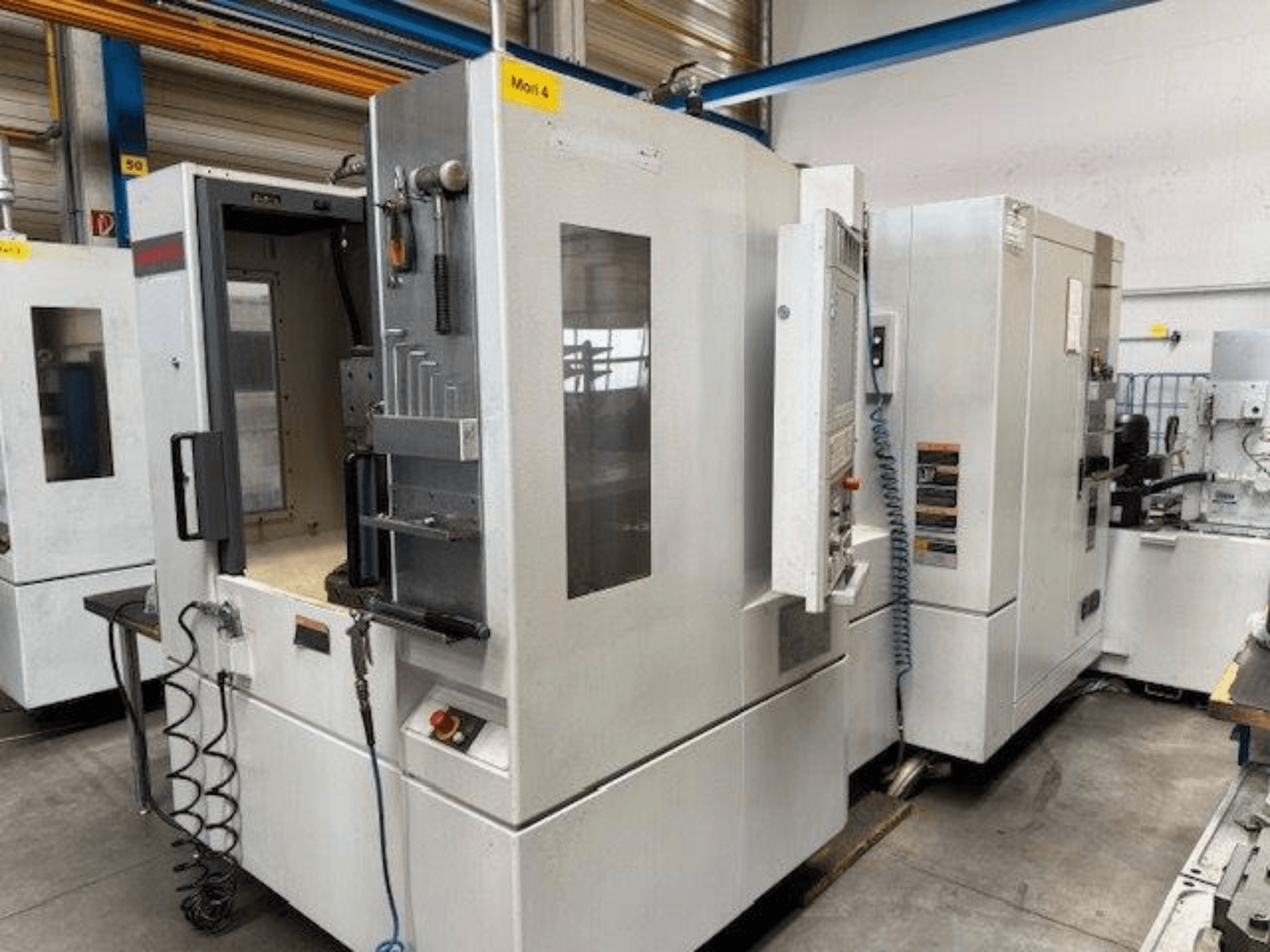 Centre d'usinage horizontal MORI SEIKI NH4000 DCG présenté de face, avec une porte ouverte et des détails du panneau de commande.