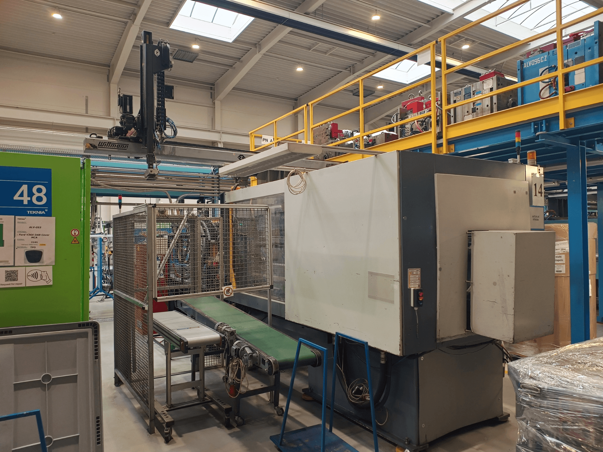 Machine d'automatisation industrielle de Winmon, vue latérale montrant le convoyeur, le panneau de commande et la cage de sécurité dans une usine.