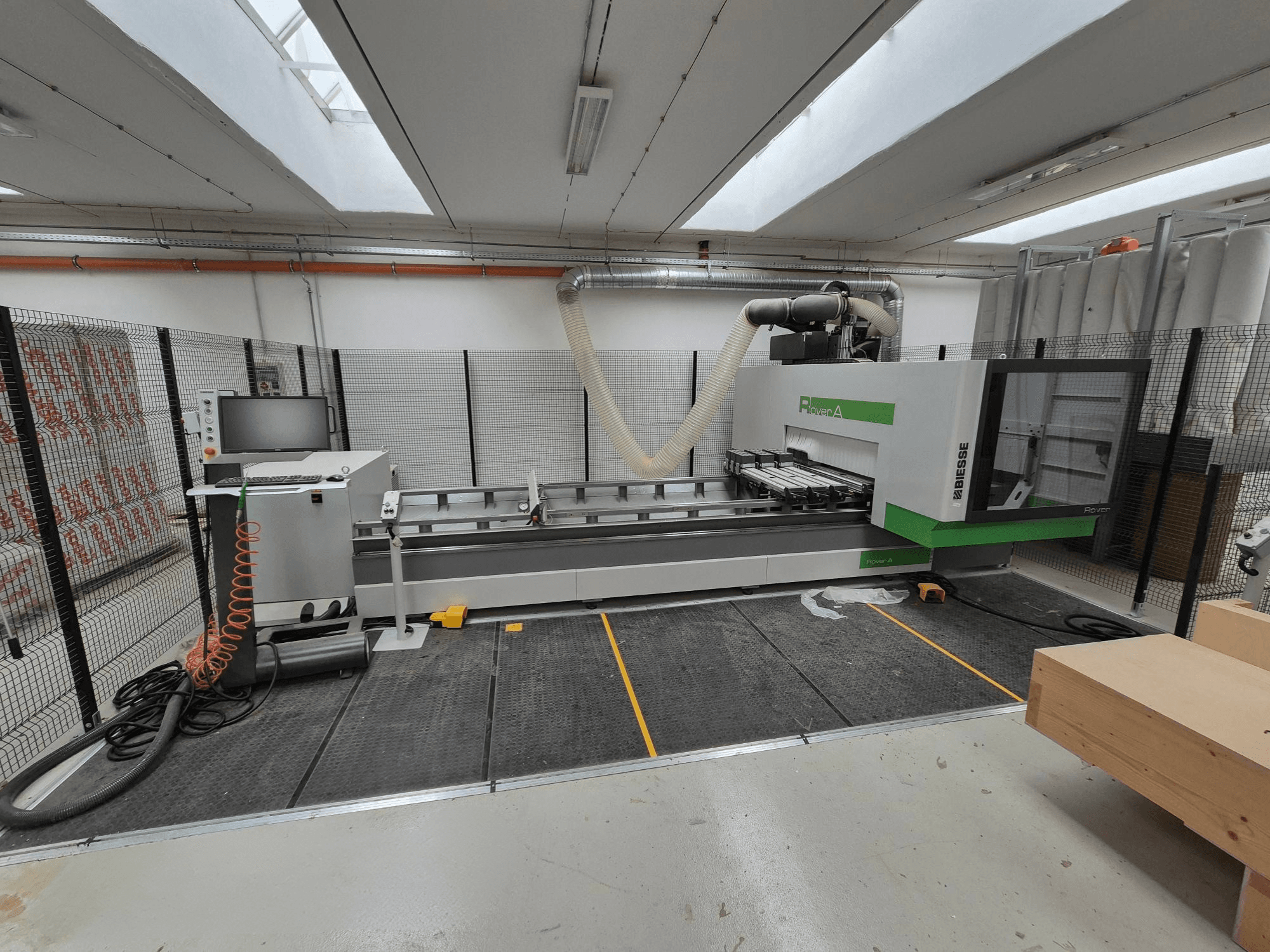 Biesse Rover Une machine CNC dans un atelier, vue de face. Elle comporte un panneau de commande, un système d'aspiration et un plan de travail.