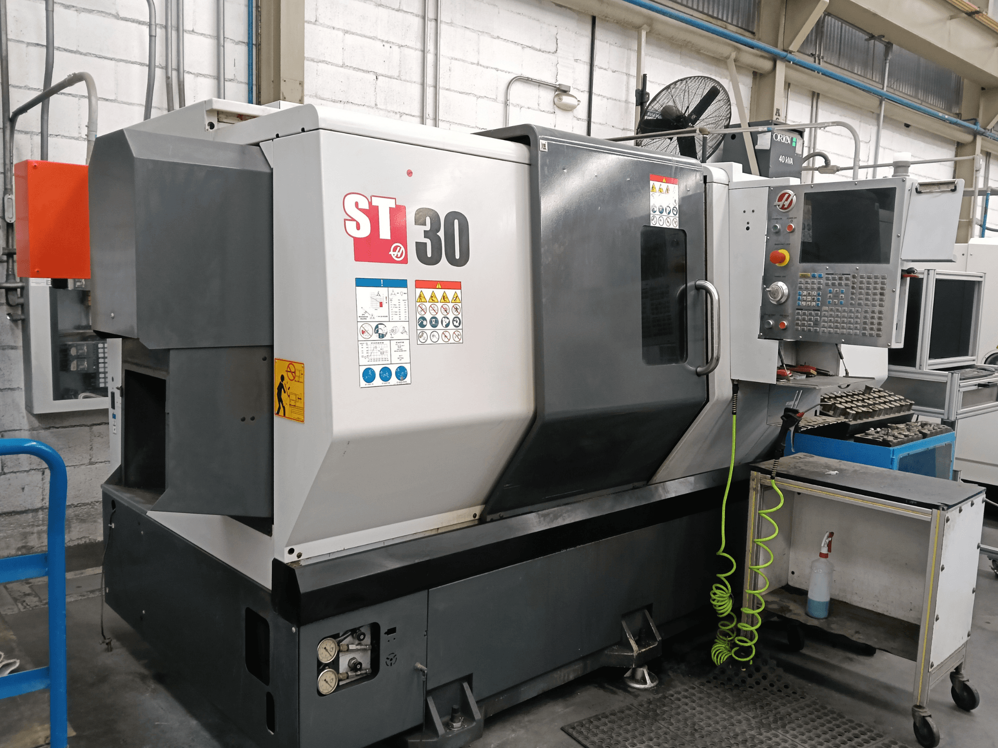 Texte alternatif : Vue de face du tour horizontal HAAS ST-30, avec son panneau de commande, ses étiquettes de sécurité et des outils posés sur un chariot à proximité.