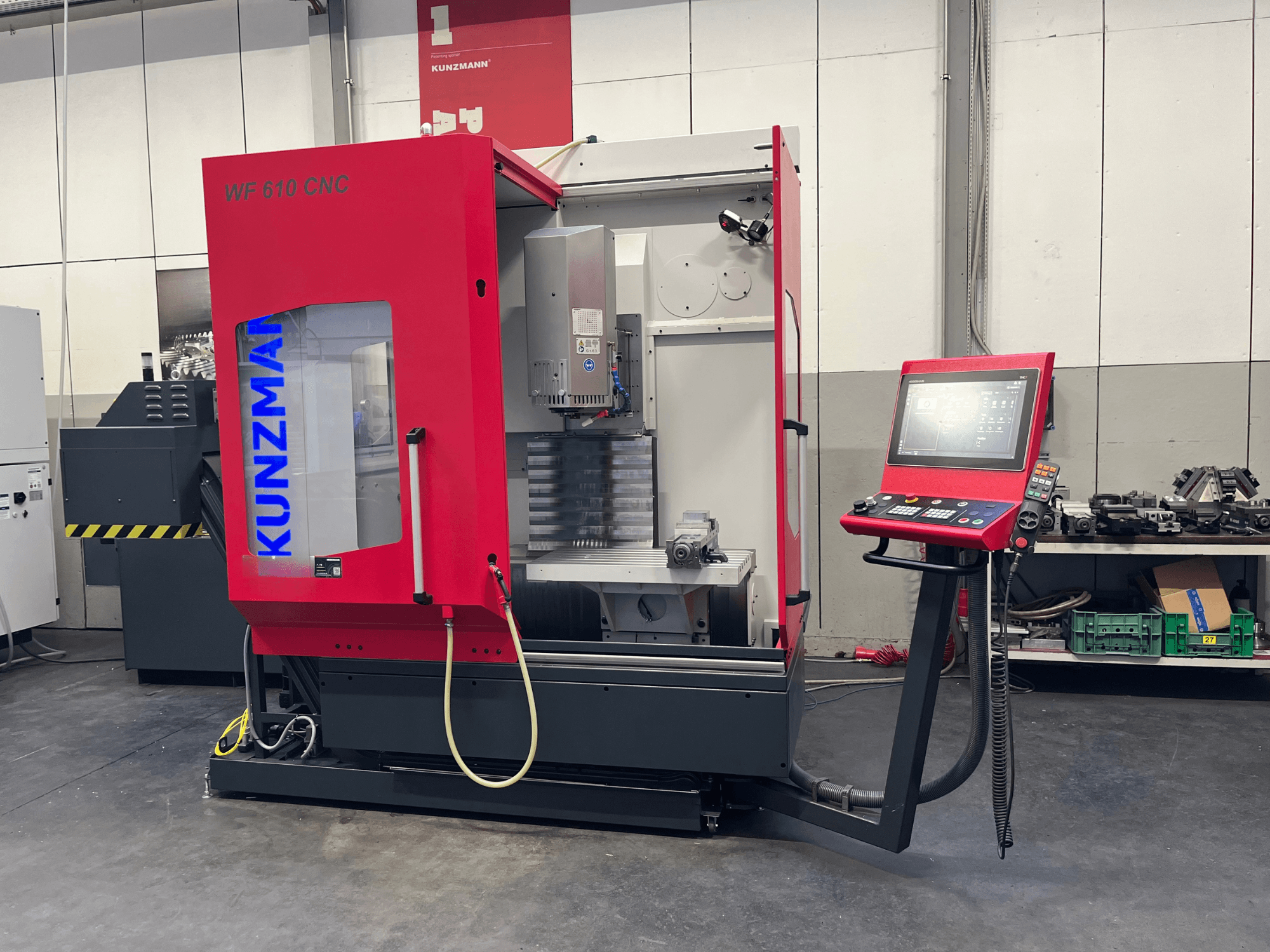 Centre d'usinage vertical CNC KUNZMANN WF 610 dans un atelier, avec son panneau de commande et ses composants visibles.