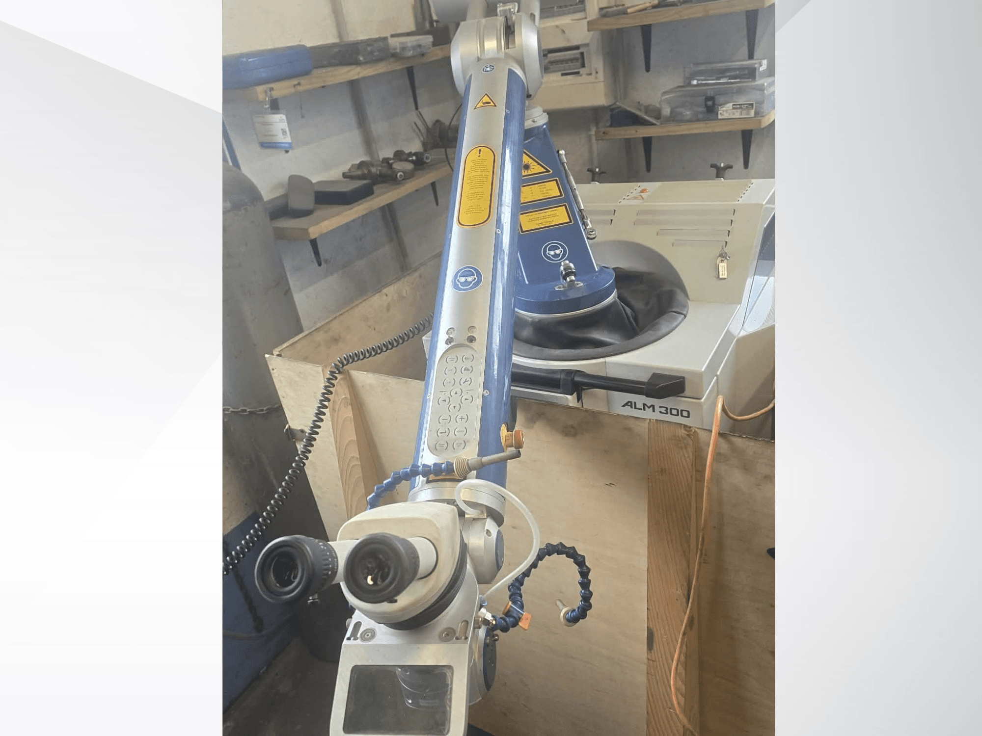 Vue de face de la machine de soudage laser ALPHA LASER ALM 300, équipée d'un bras robotisé, de lentilles optiques et d'un panneau de commande.