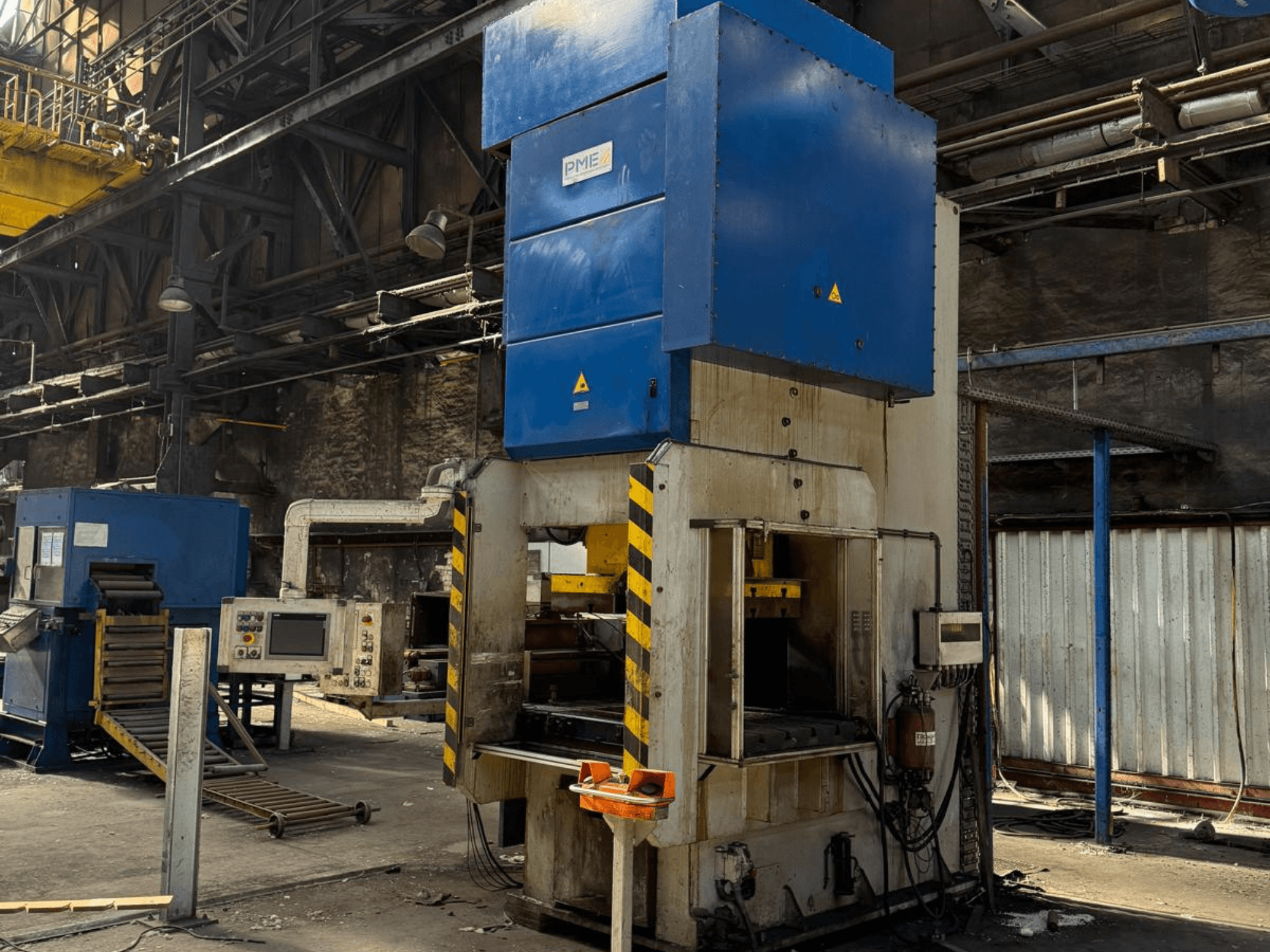 Presse mécanique de découpage PME PE 400-1700 C, vue de face, montrant la partie supérieure bleue et la base à rayures jaunes dans un environnement industriel.