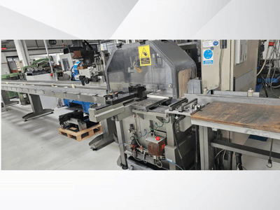 Machine de découpe industrielle vue de côté, avec un long convoyeur, un panneau de commande et des avertissements de sécurité.