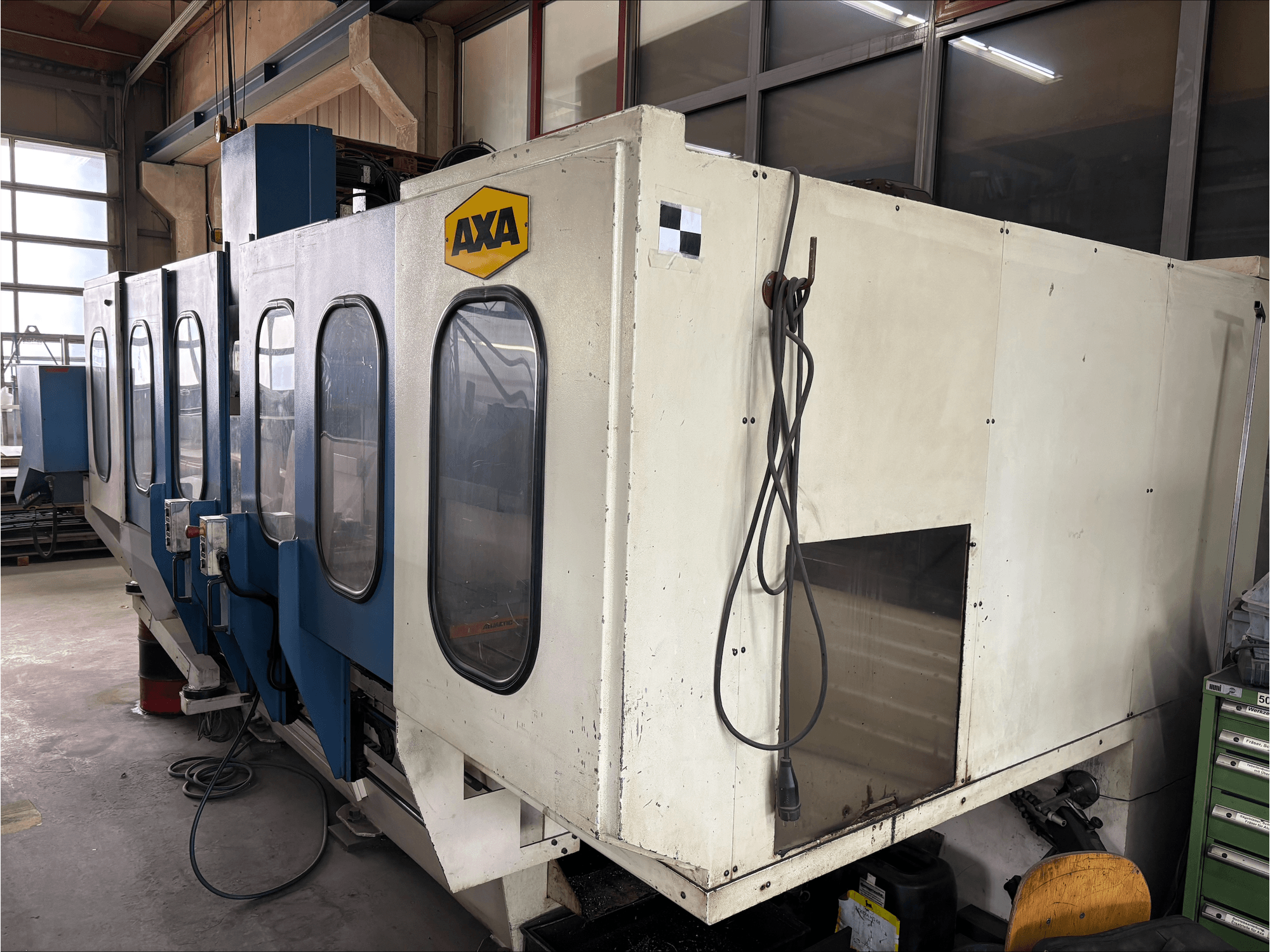 Centre d'usinage vertical AXA VSC-1-M/C, vue de face, avec une grande armoire blanche et un panneau de commande bleu.