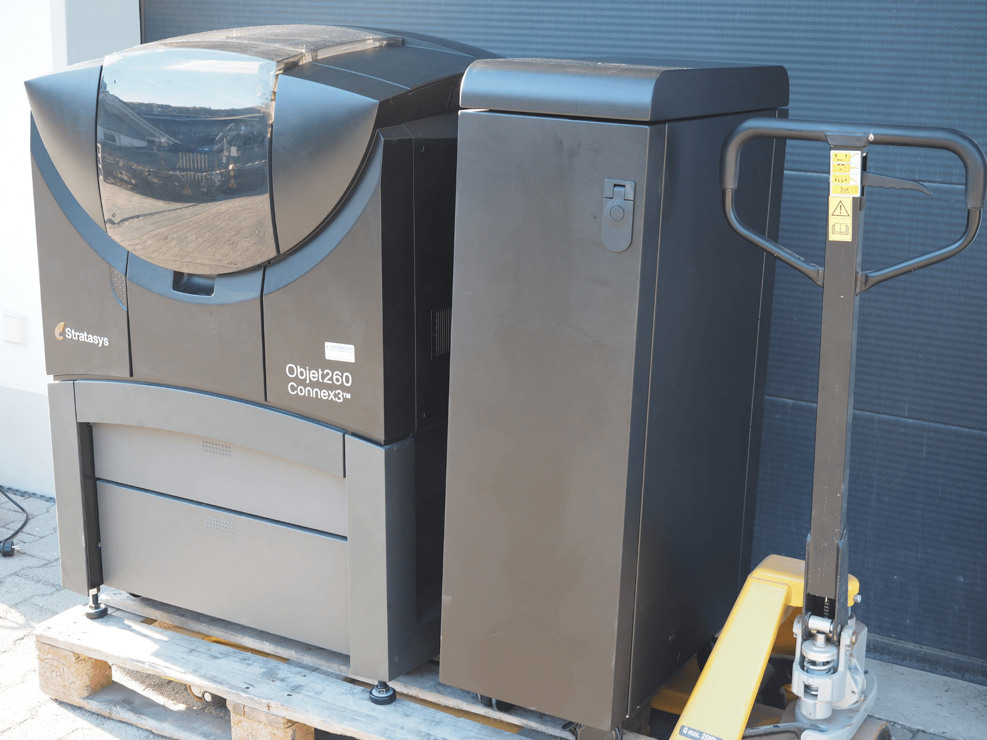 L'imprimante 3D plastique Stratasys Objet260 Connex3, vue de côté, présente un design compact avec un panneau de commande et un bac à matériaux connecté.