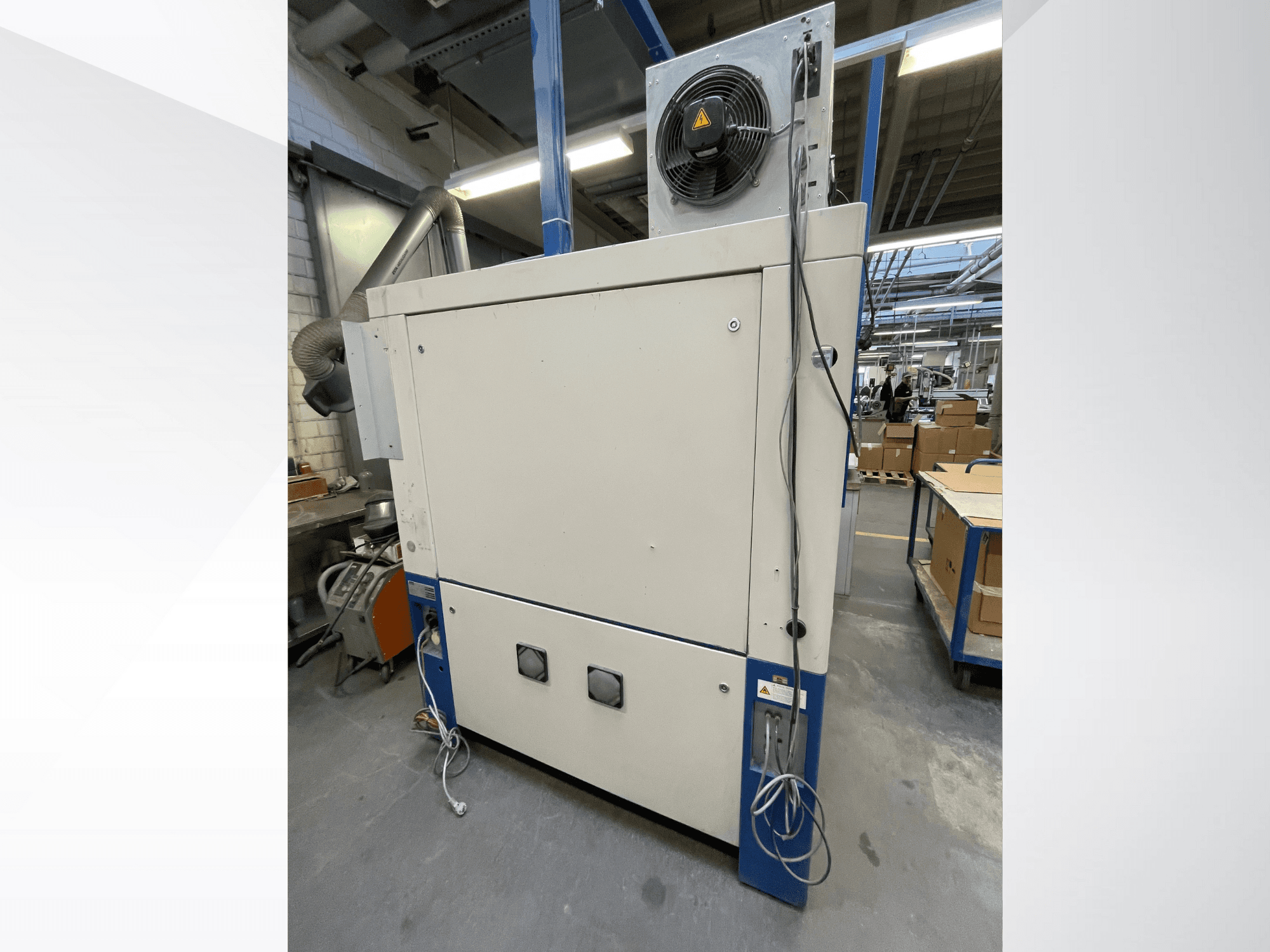 Machine de séchage industrielle avec ventilateur, vue de côté ; elle est dotée d'une ventilation et de multiples connexions électriques. Marque/modèle non visible.